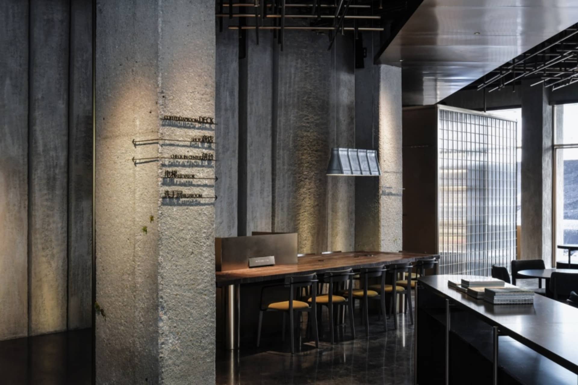 A modern industrial coffee shop interior with concrete walls, glass partitions, and steel accents.
