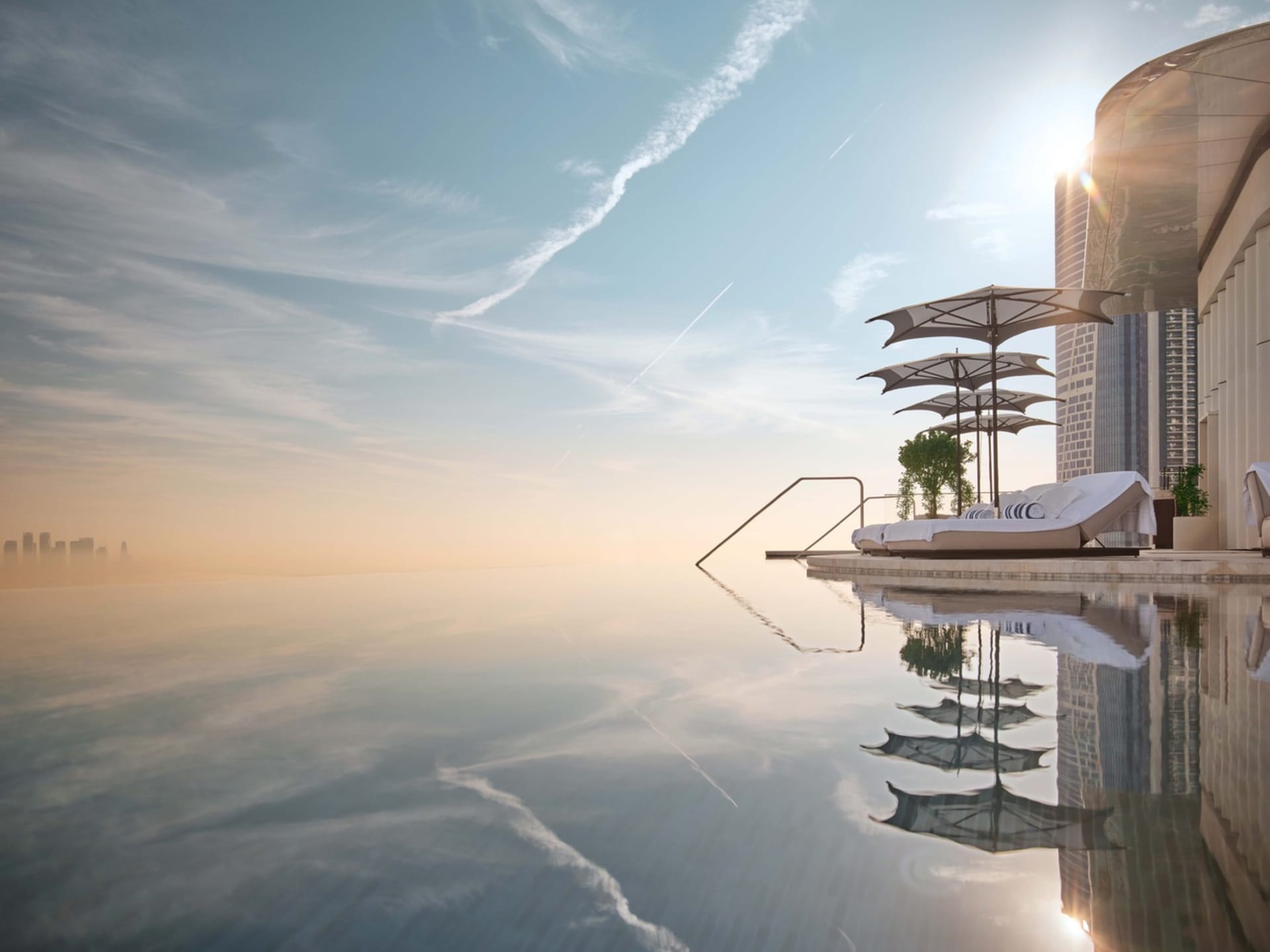 Luxurious poolside seating area with infinity pool, metal frame, concrete ground, and glass railings