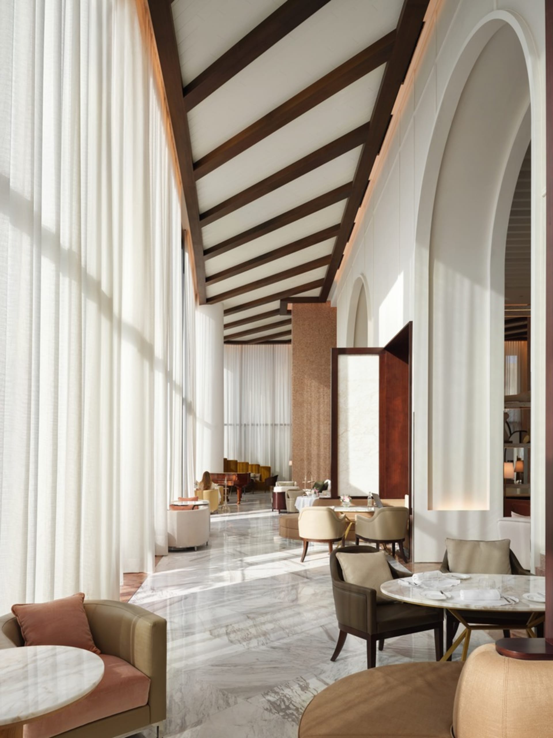Image of a modern hotel lounge featuring glass, marble, and wood materials.