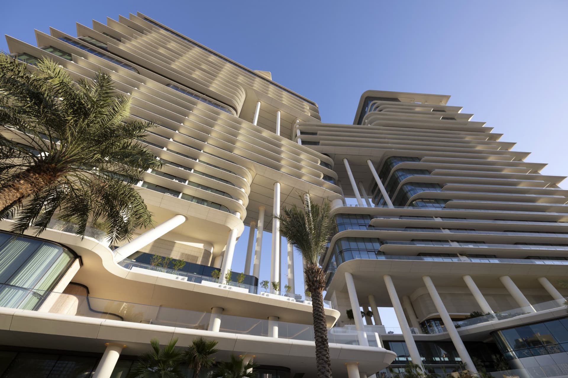 Modern residential building with concrete facade, glass windows, and steel beams.