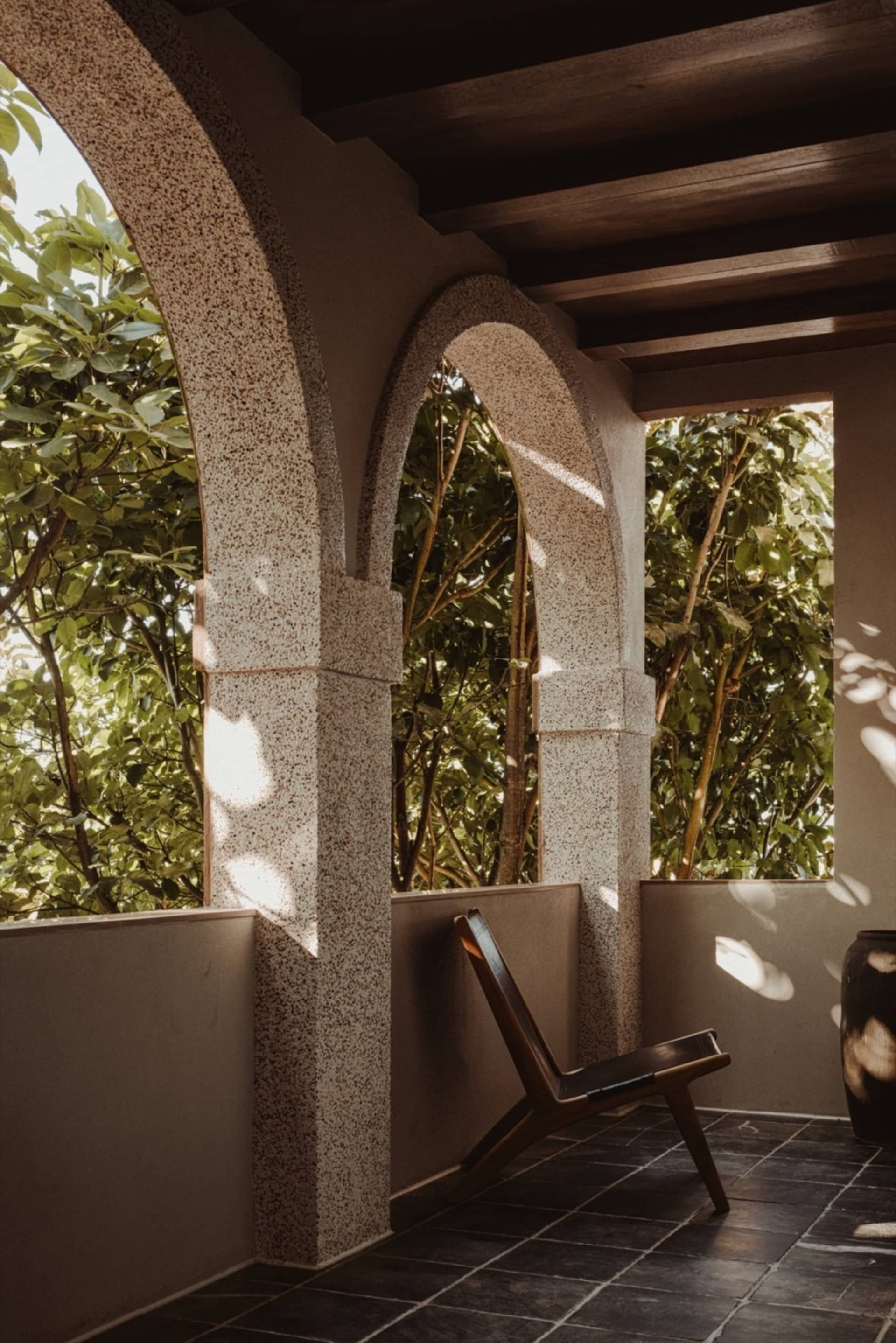 A spacious patio with decorative concrete columns and a wooden chair.