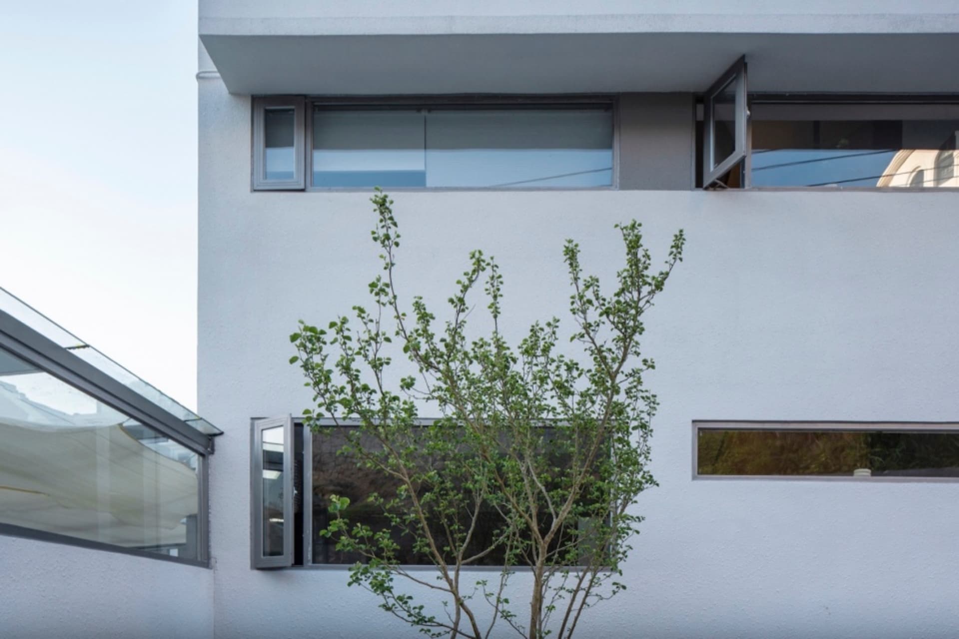 A minimalist building with white cladding and glass windows, showcasing clean lines and modern design.