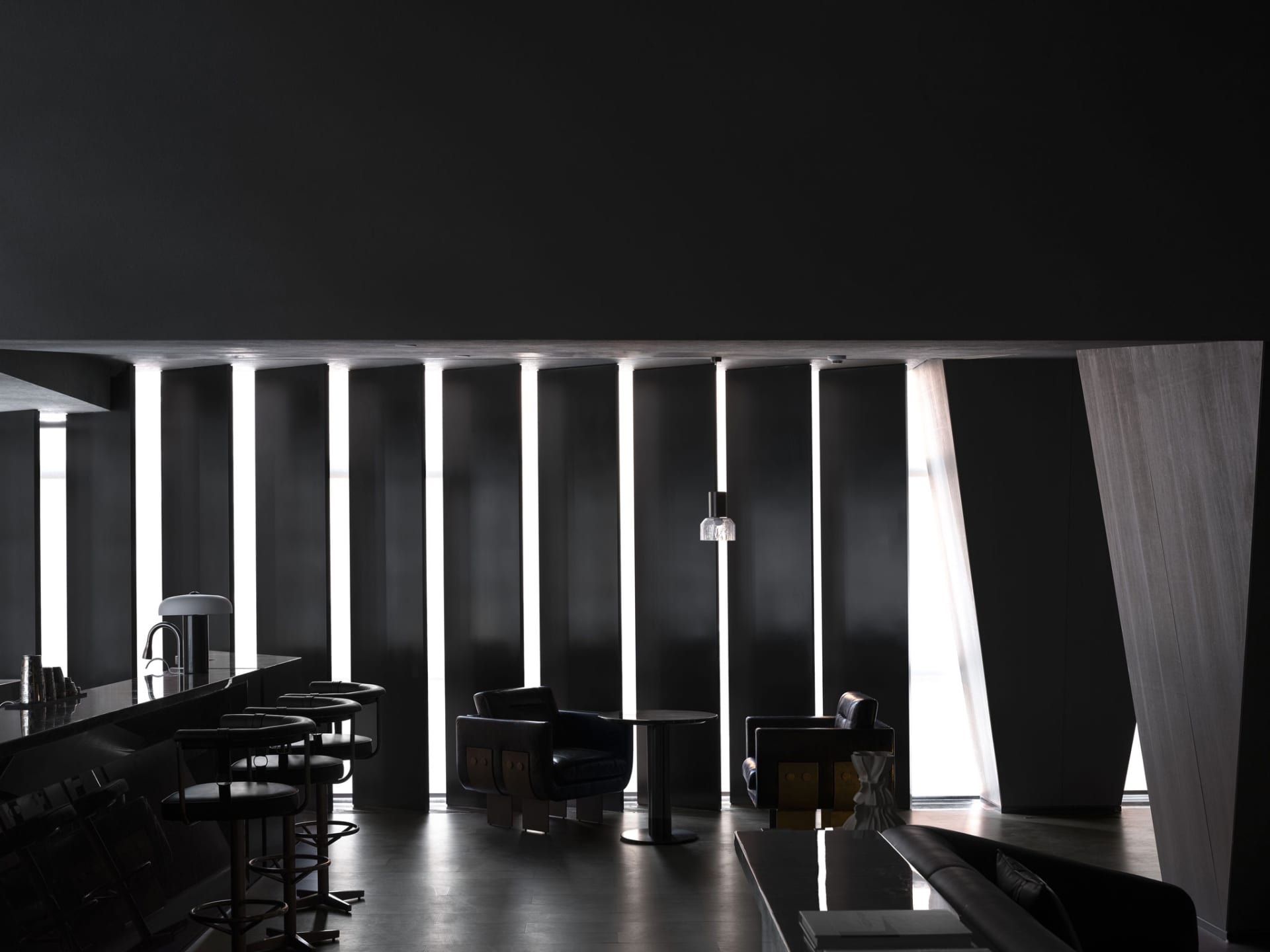 A modern, minimalist restaurant bar lounge with metallic furniture and dark lighting.