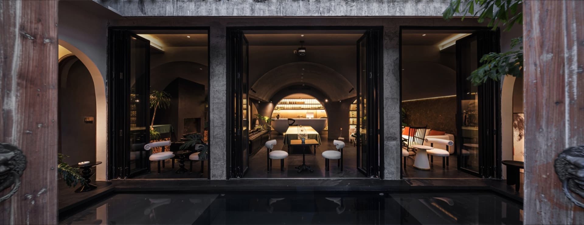 Industrial-themed restaurant lounge with concrete walls, glass dining area, and modern decor.