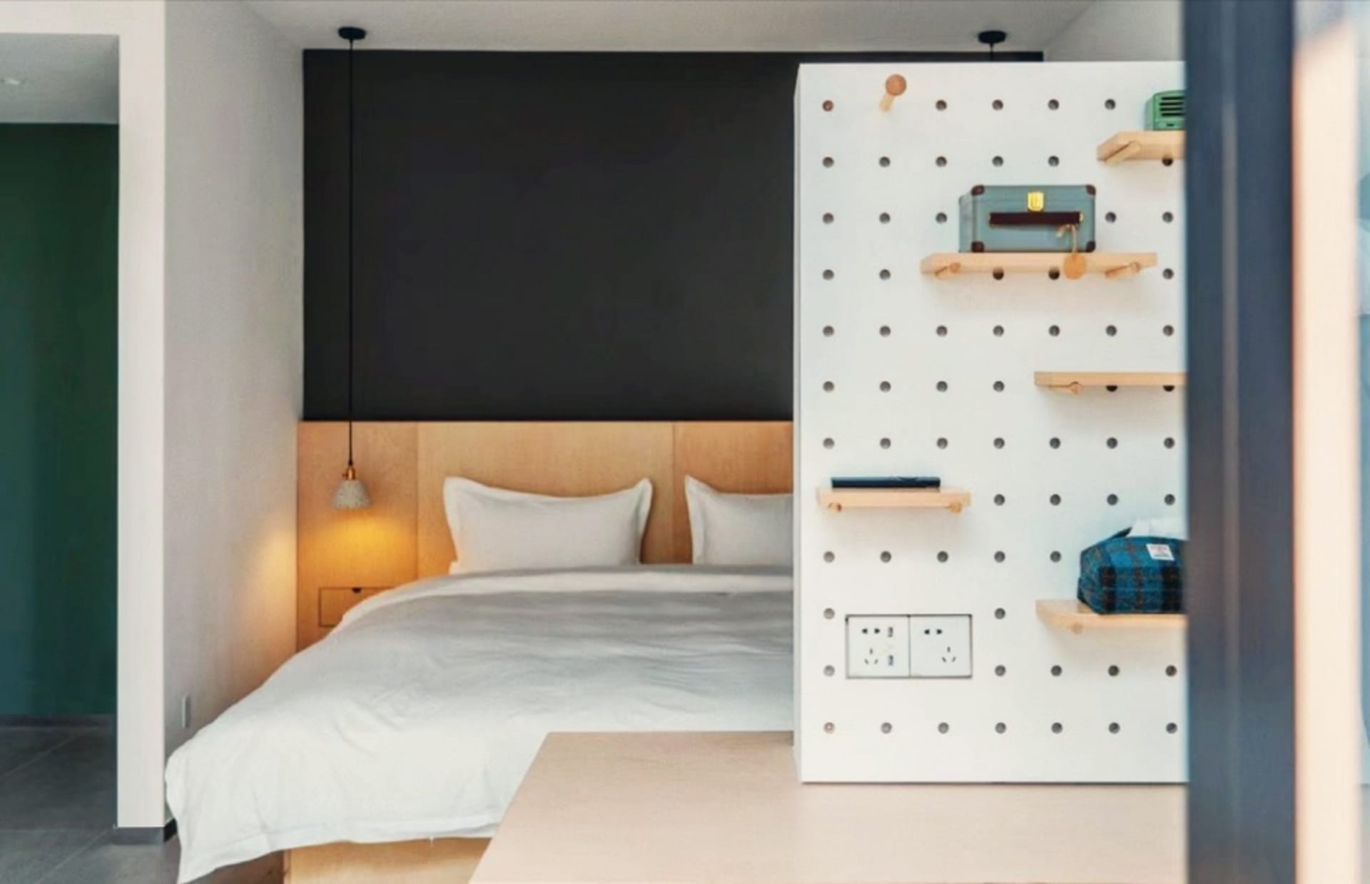 Modern minimalist bedroom with a bed featuring white bedding and a white wooden headboard, illuminated with warm lighting fro