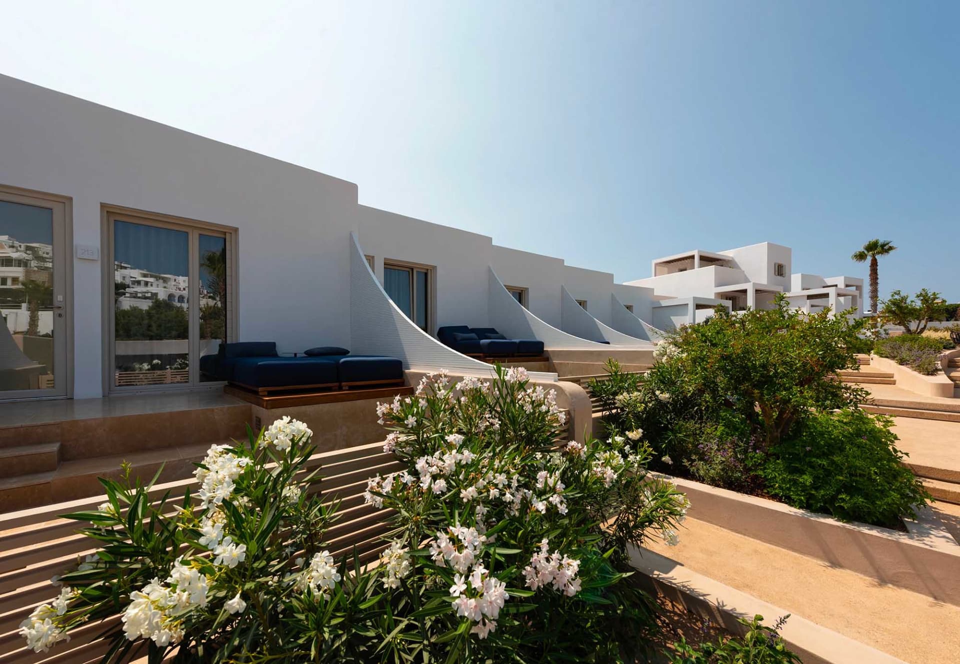 Modern residential exterior with white stone exterior and blue cushioned patio furniture.