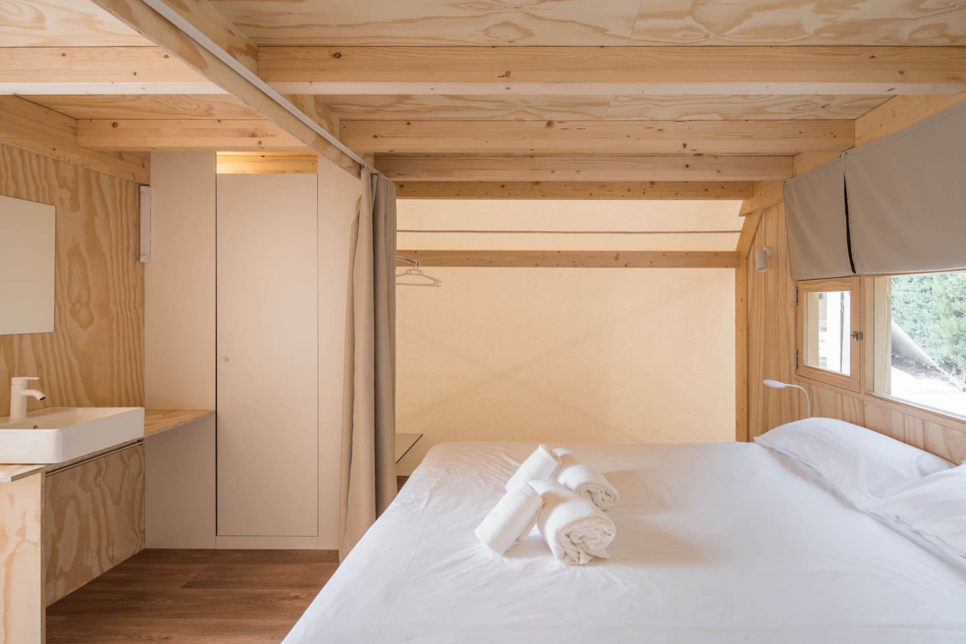 A minimalist bedroom with wooden elements, white linens, and a simple design.