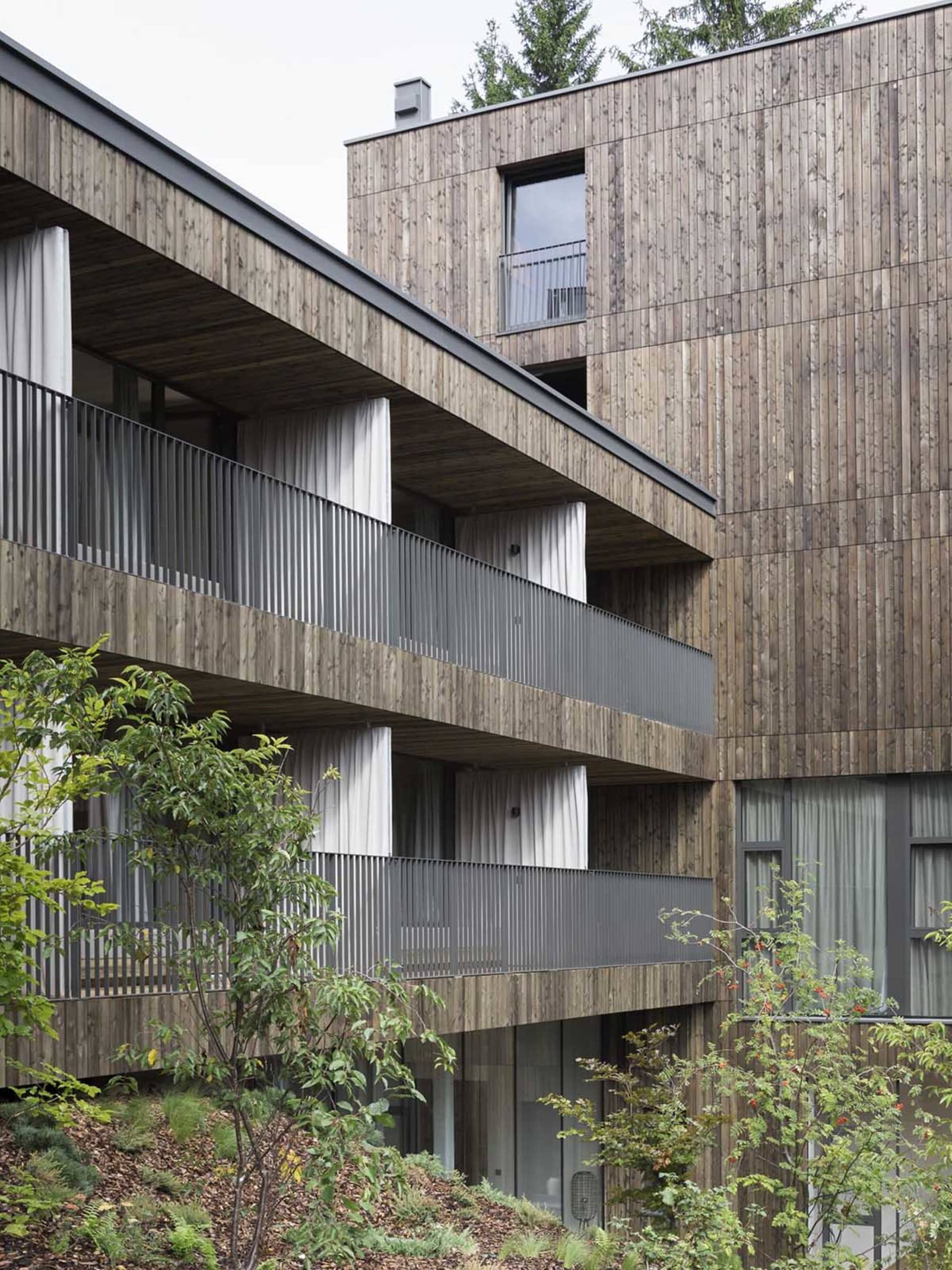 一座外觀採用木質建材的現代住宅大樓,設有多個陽台。