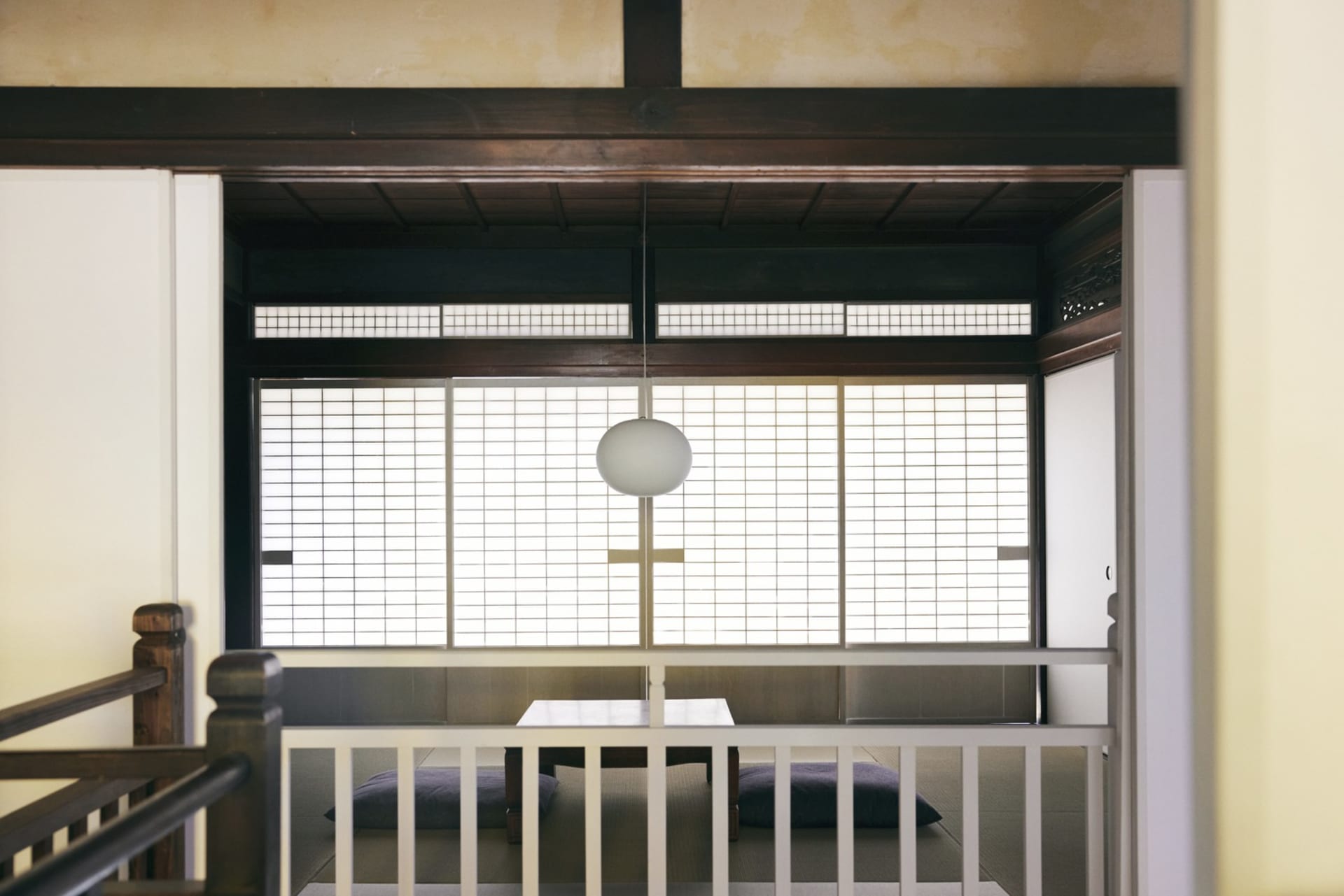 White-themed interior space featuring traditional Japanese sliding paper screens behind a contemporary table and stool arrang