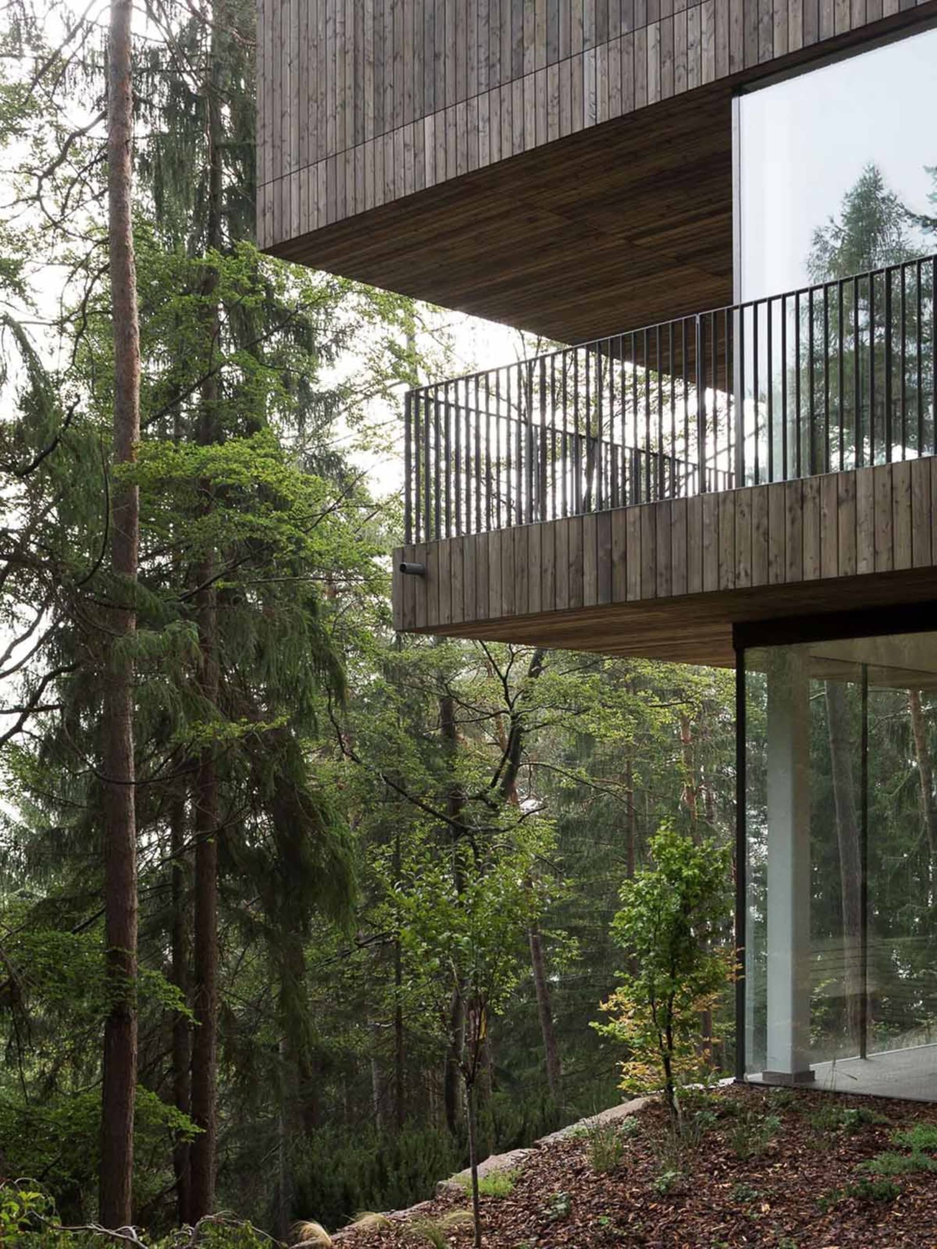 A modern treehouse designed for forest-oriented living, featuring wooden exteriors and glass walls.
