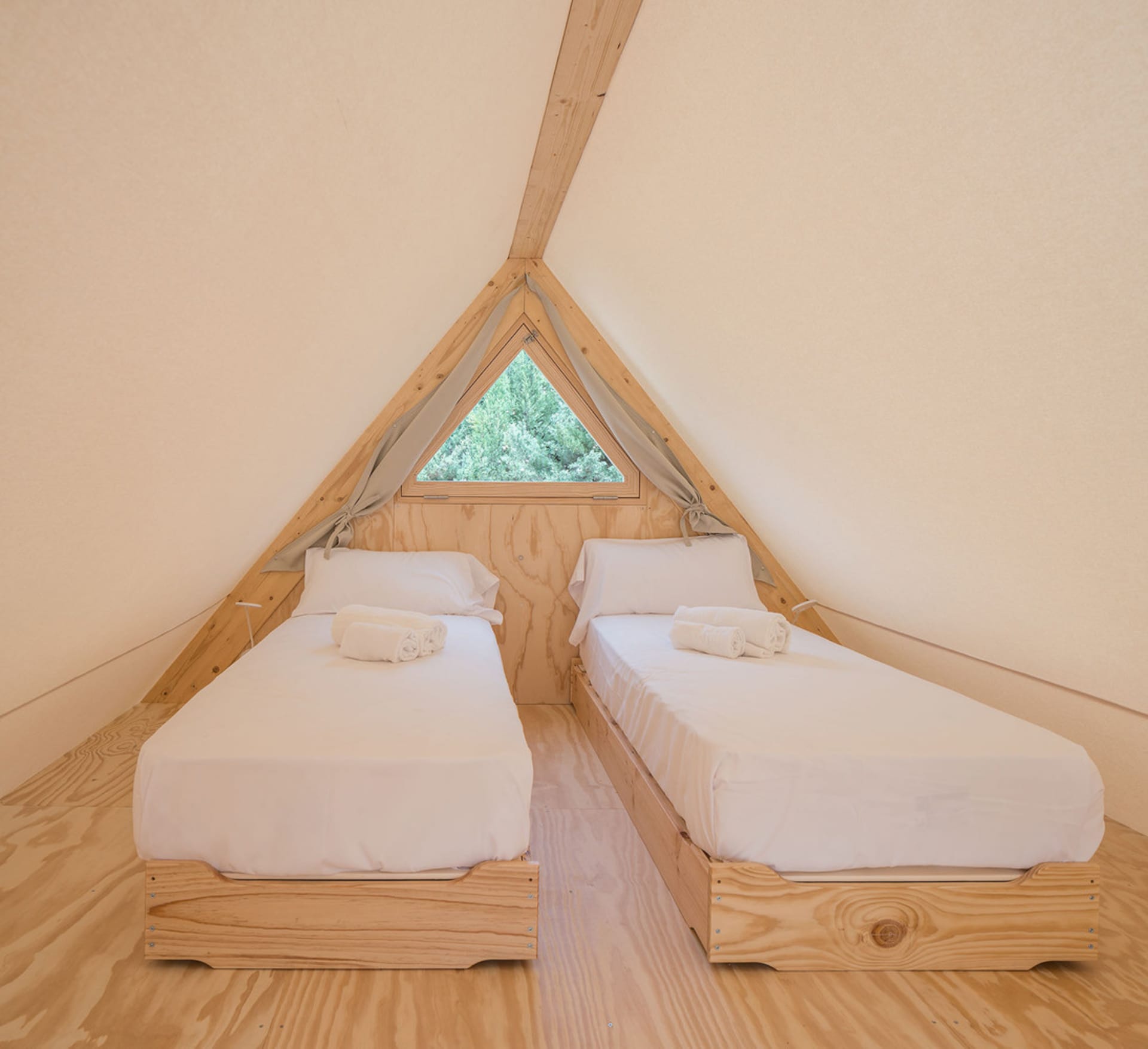 A minimalist bedroom with triangle-shaped windows, featuring twin beds with white bedding and natural wooden elements.