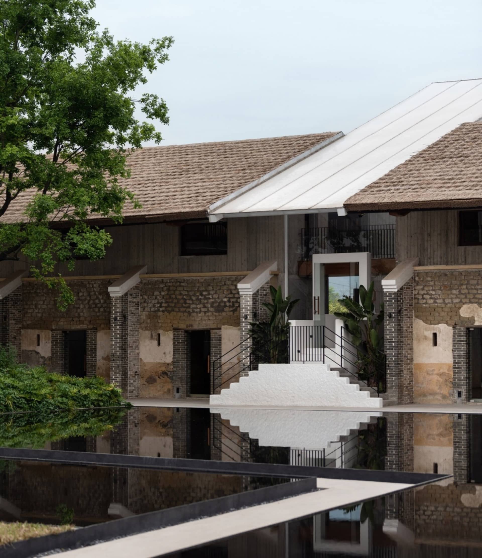 A modern building with concrete exterior and roof reflection in a pool.