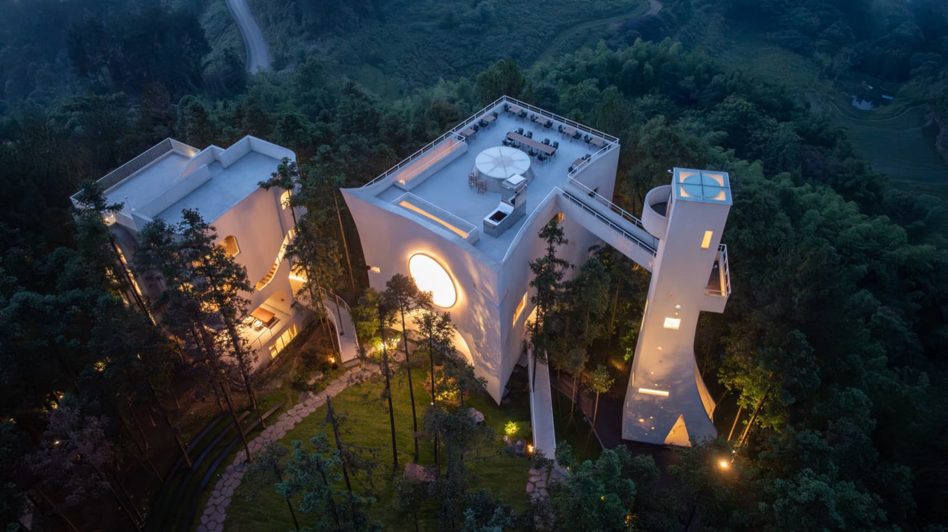 俯瞰一座現代簡約建築,外牆為混凝土材質,屋頂設有大型圓形天窗。