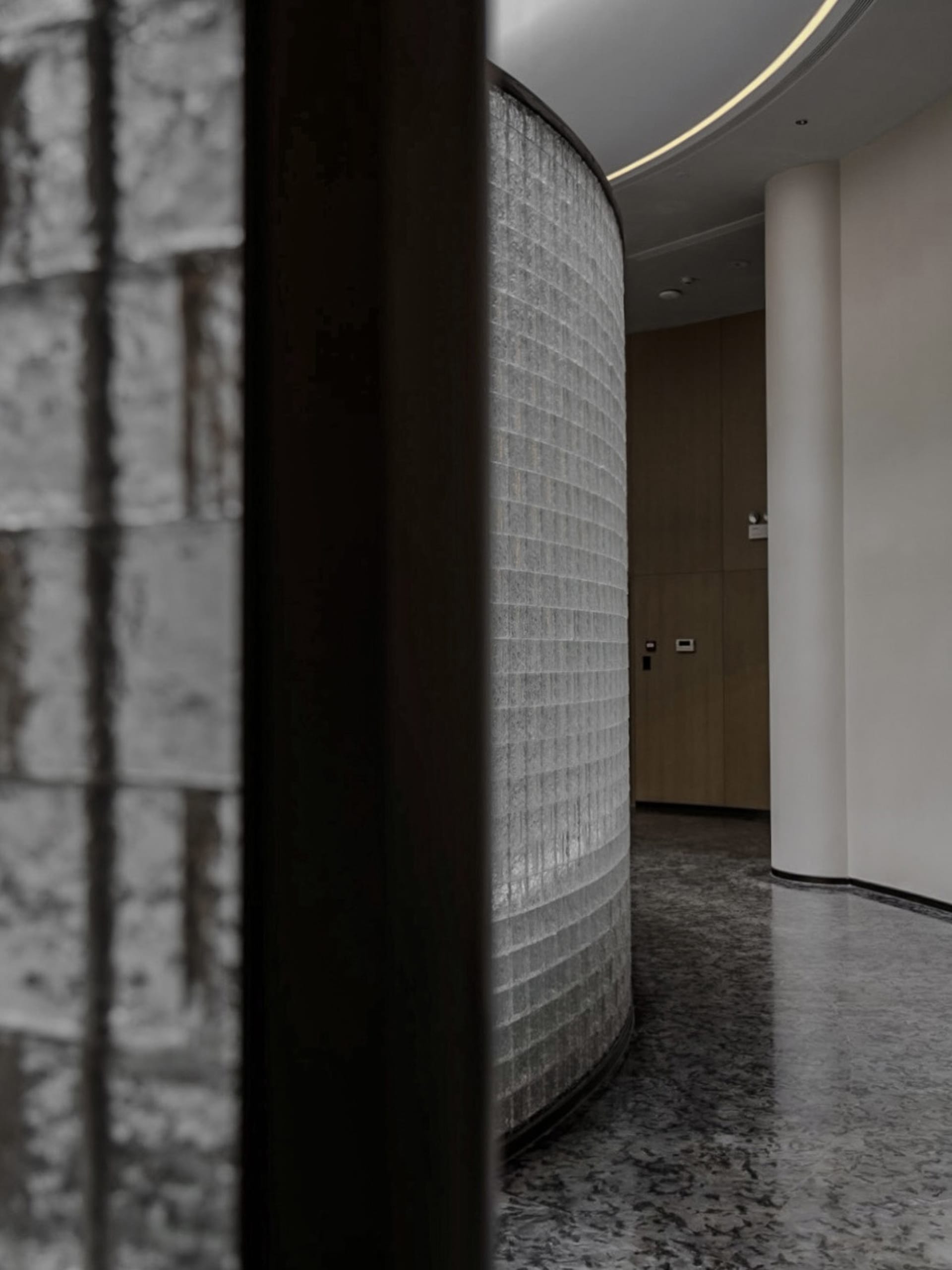 Modern interior hallway with granite columns and a curved wall.