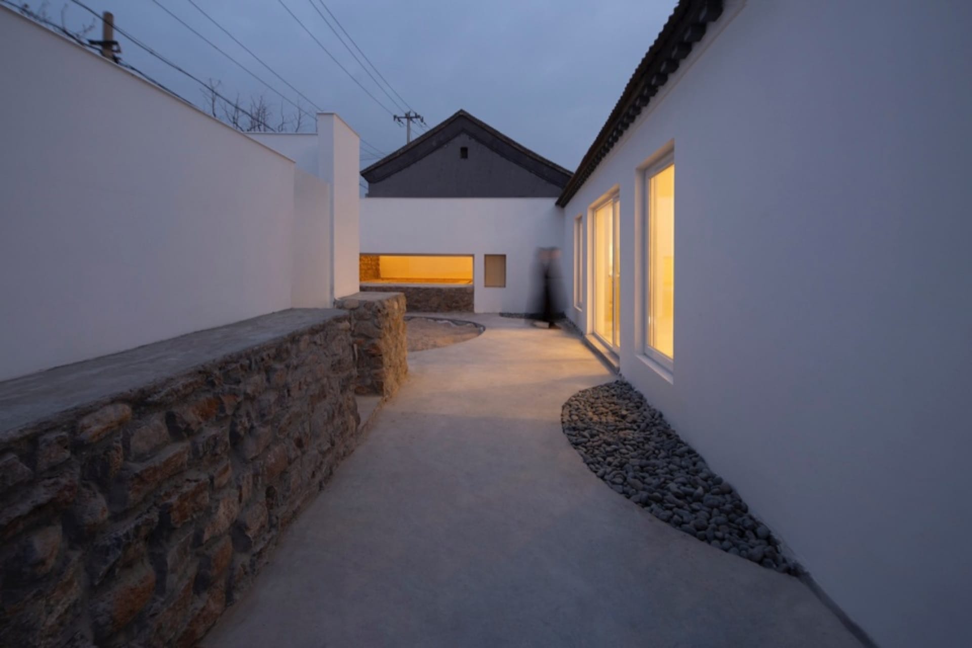 A contemporary residential exterior featuring concrete walls, stone accents, and a landscaped garden.