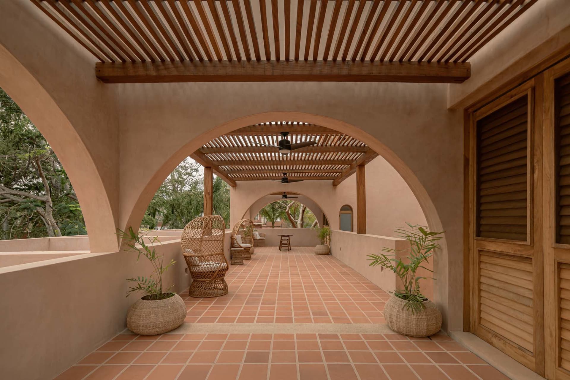 A serene indoor space with an arched walkway, tiled floor, and natural light pouring in through the open doors.