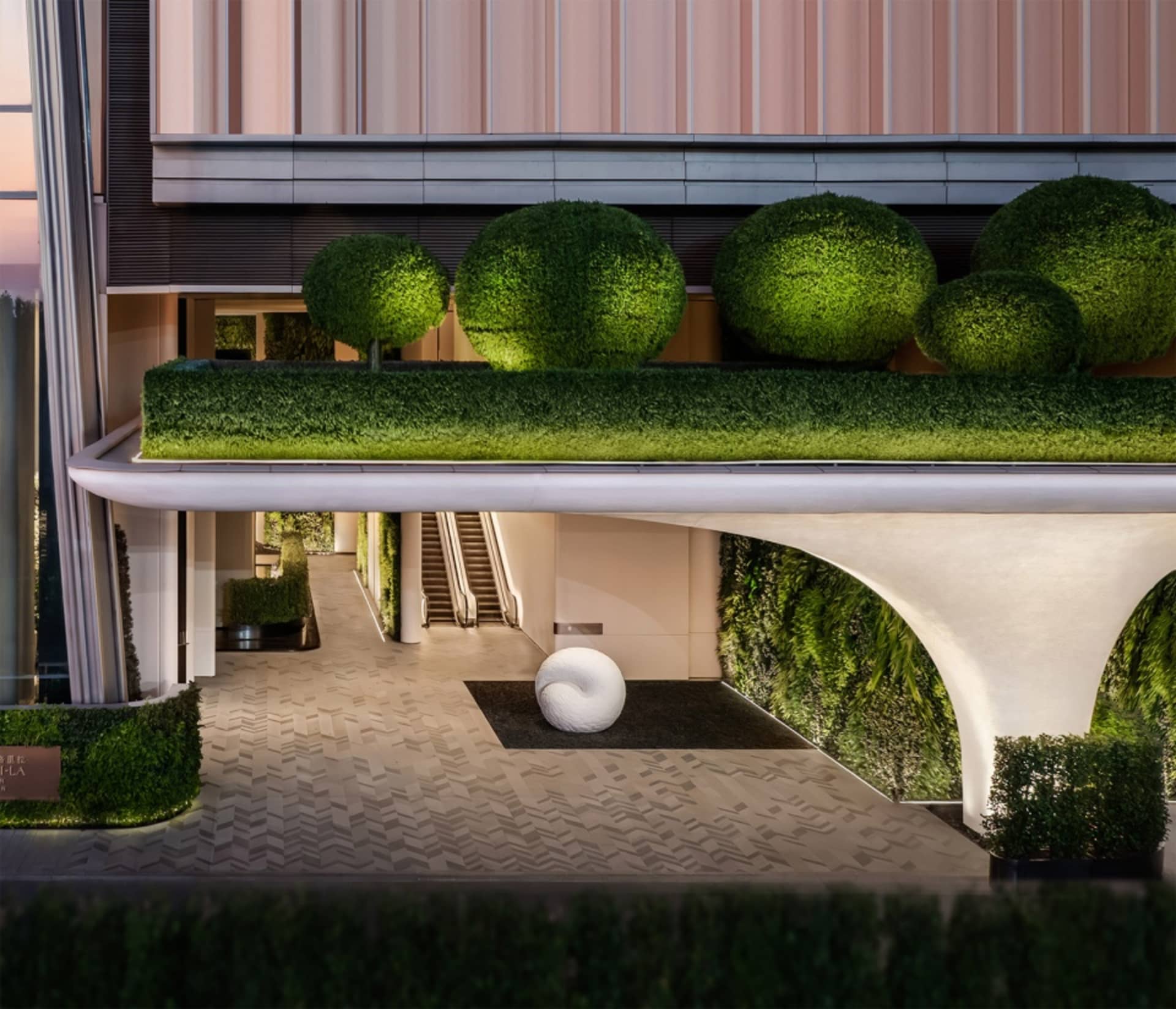 A sleek, minimalist hotel lobby designed with concrete and greenery.