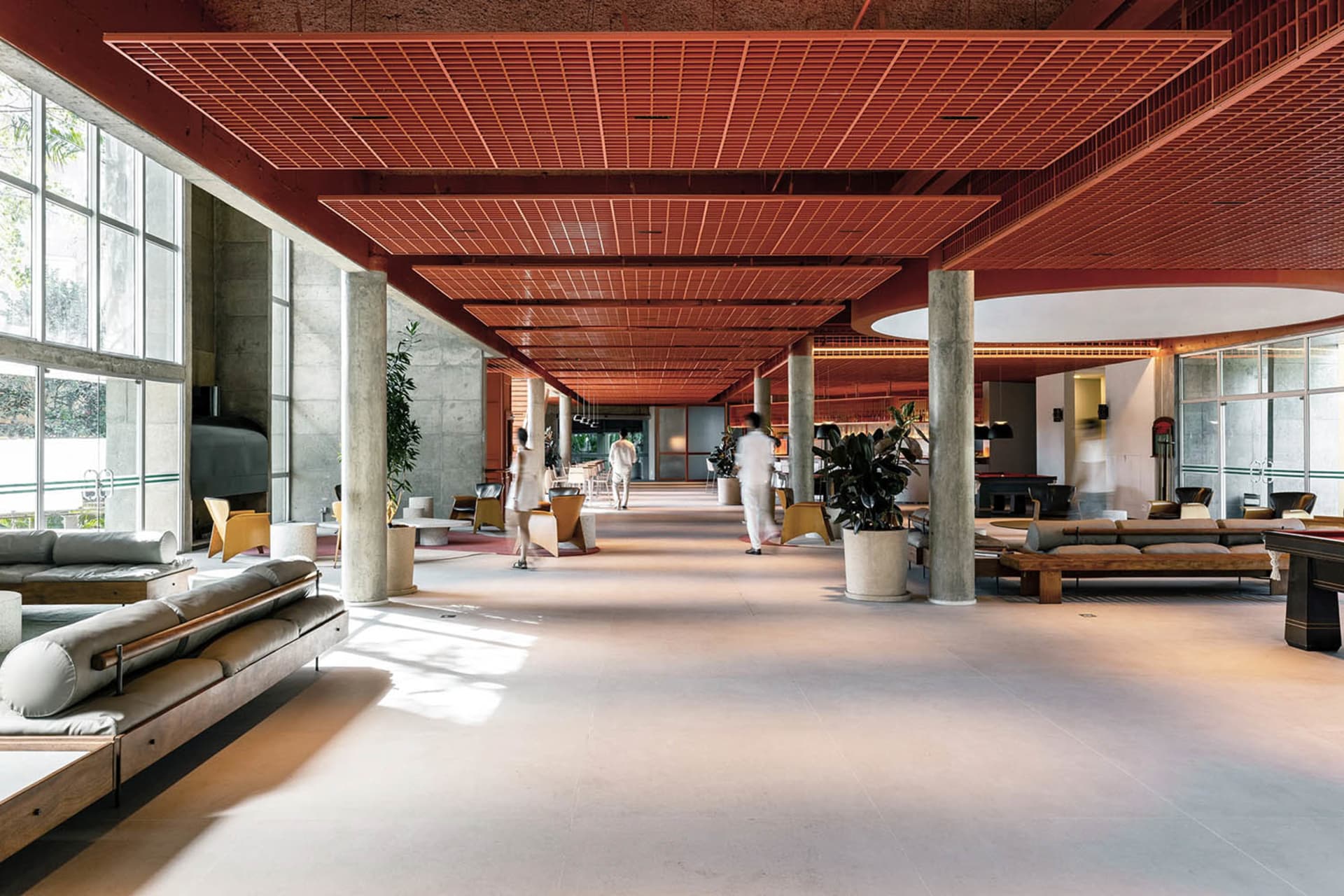 A spacious and modern lobby with concrete flooring and a grid-patterned ceiling.