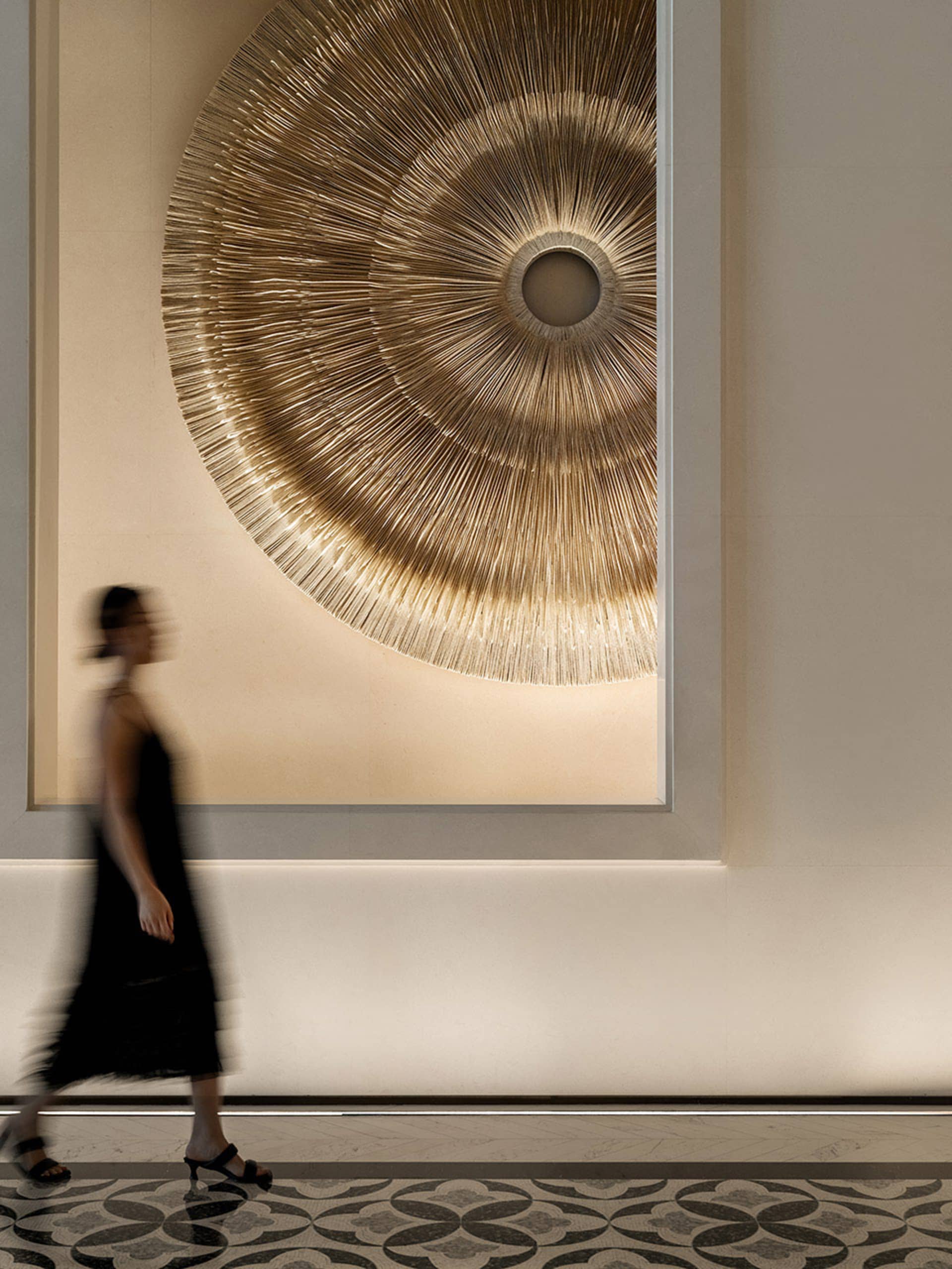 A modern lobby features a metallic-textured circular artwork hanging on the wall.