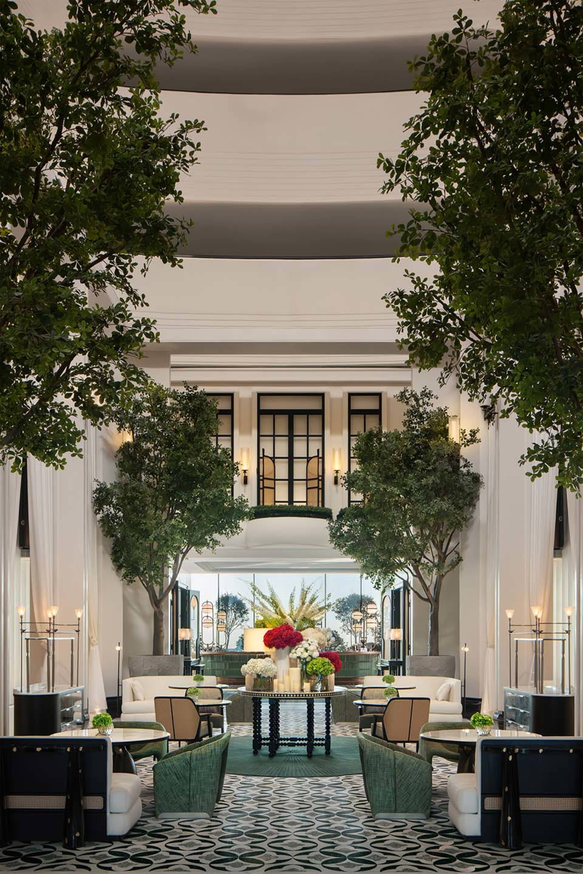 Modern lobby filled with greenery, tables, and seating areas.