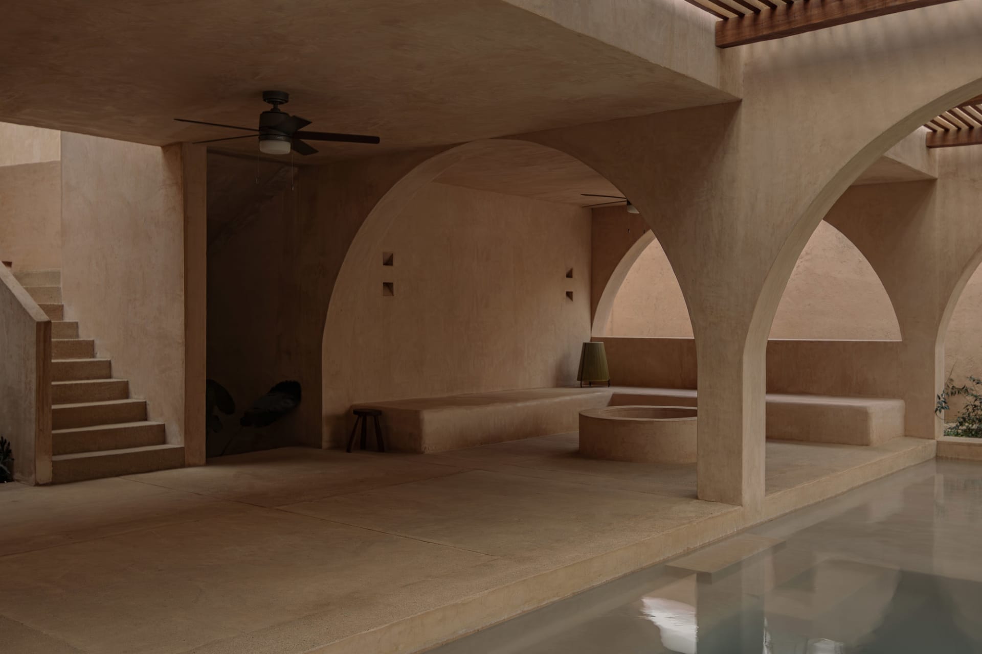 Minimalist architectural design featuring a concrete poolside with seating and a ceiling fan.