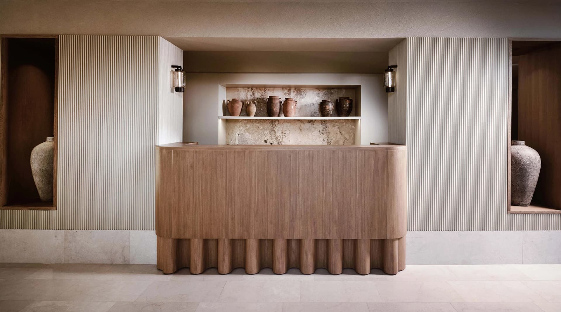 Modern reception desk with wooden panels and built-in shelves displaying ceramic vases.