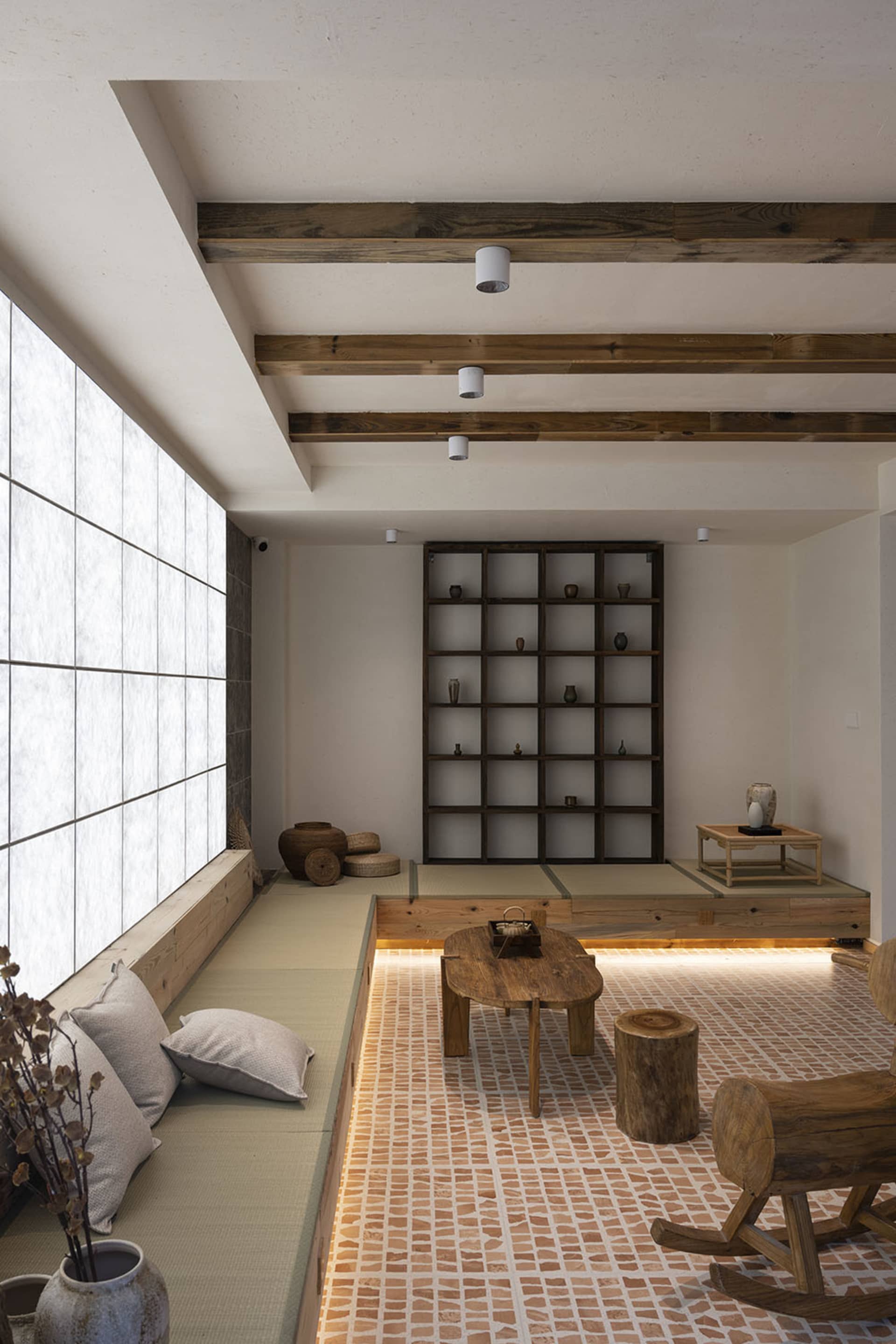 A modern minimalist living space featuring wooden furniture, stone accents, and paper cushions.