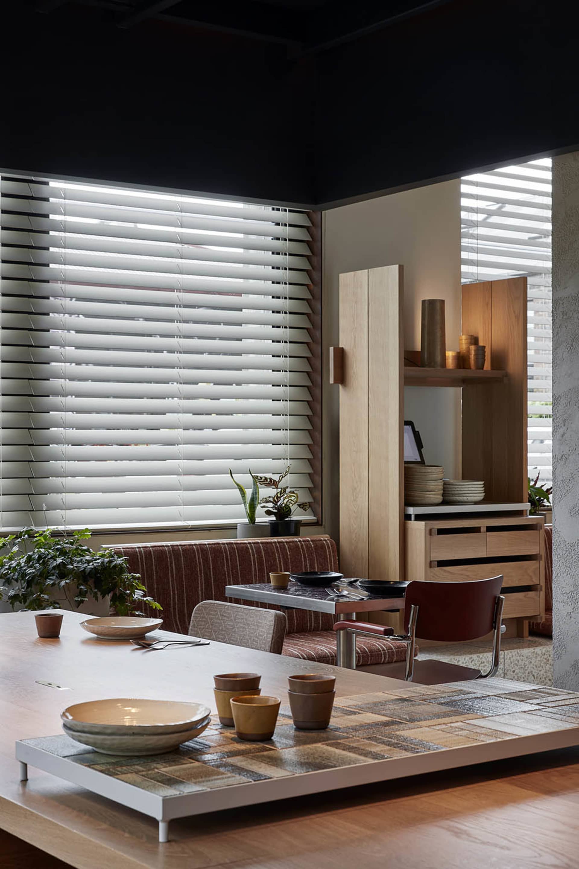 A modern industrial kitchen with wooden flooring, minimalist design, and natural light streaming through the window.