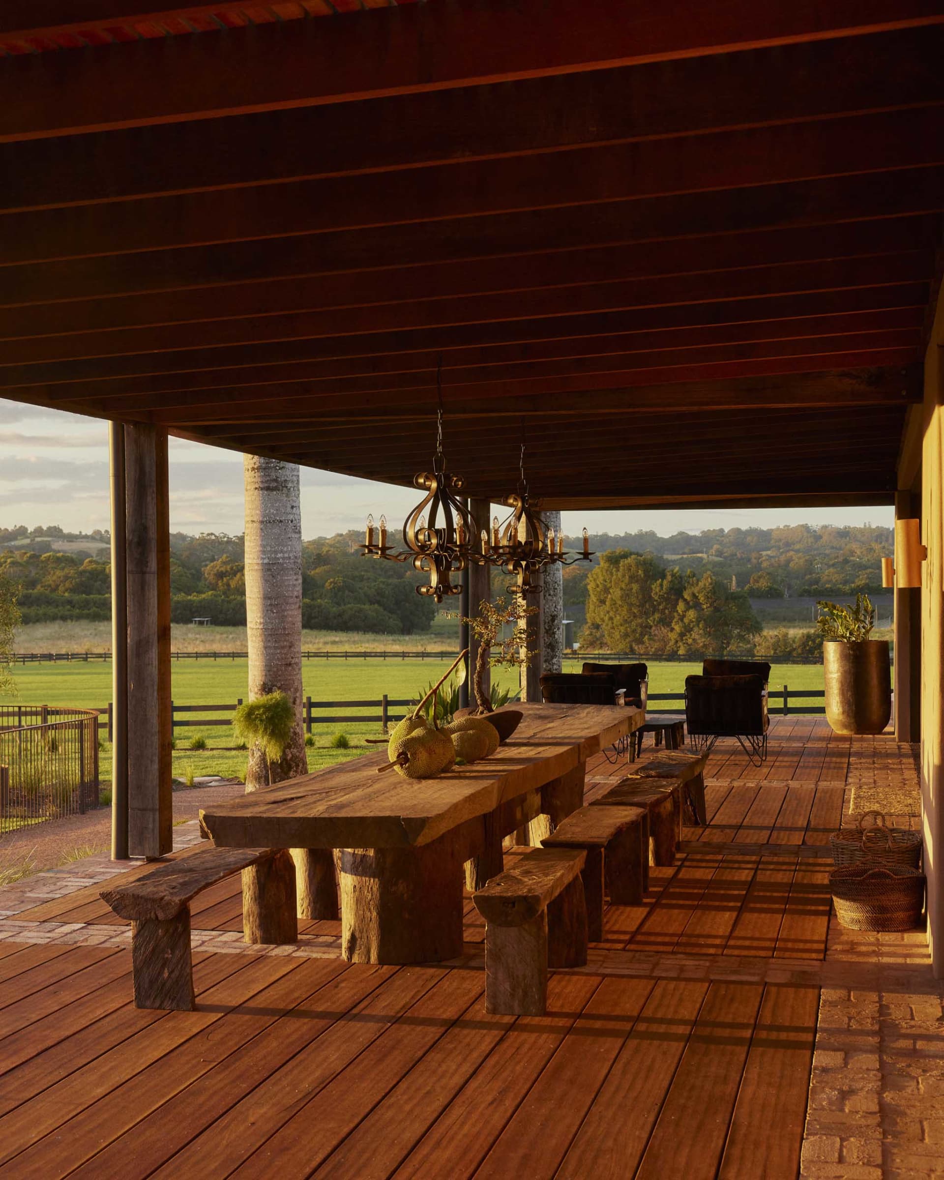 A wooden porch with furniture overlooking green fields.