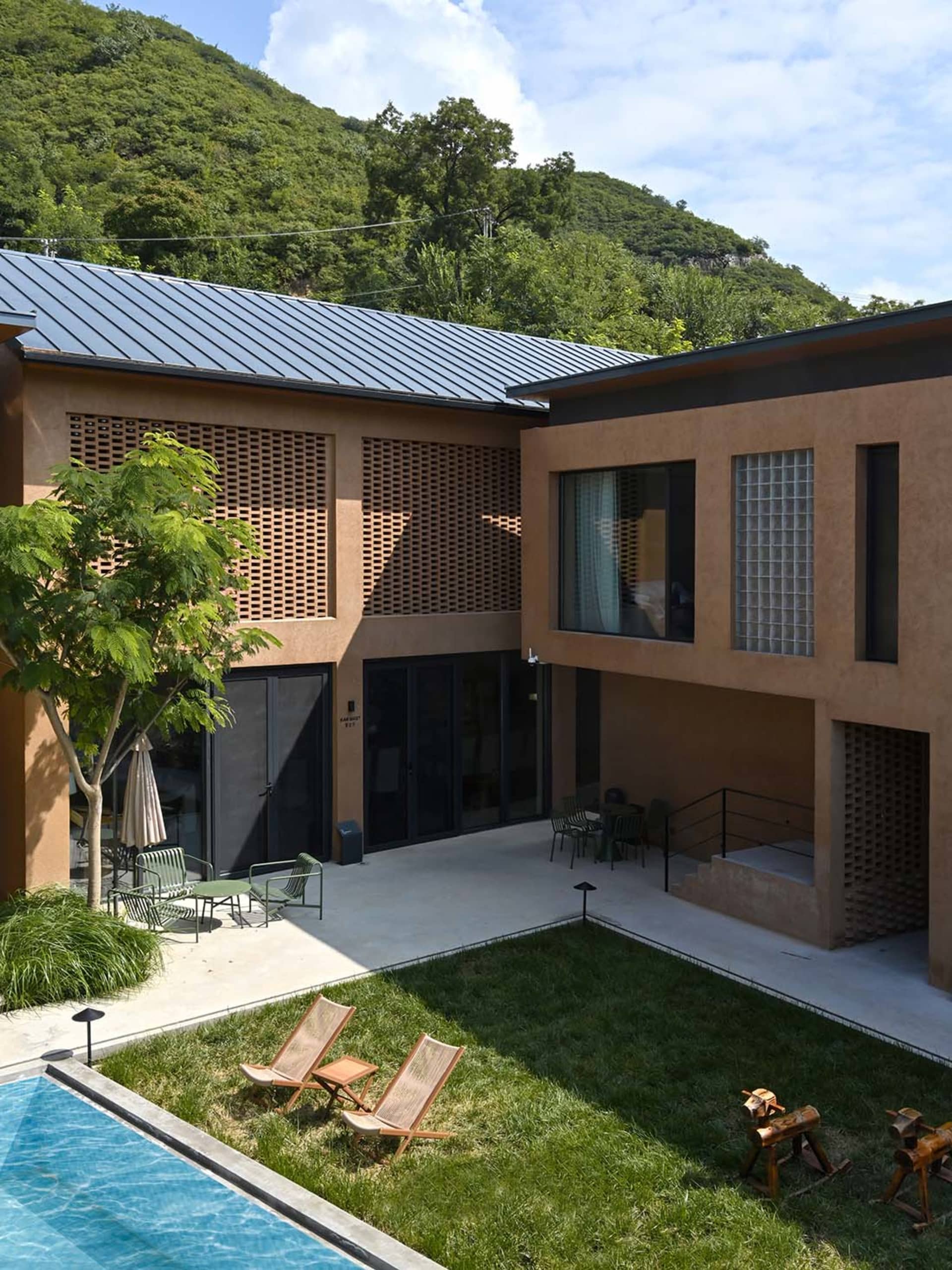 Modern residential house exterior with concrete walls, metal roof, and mountain view.
