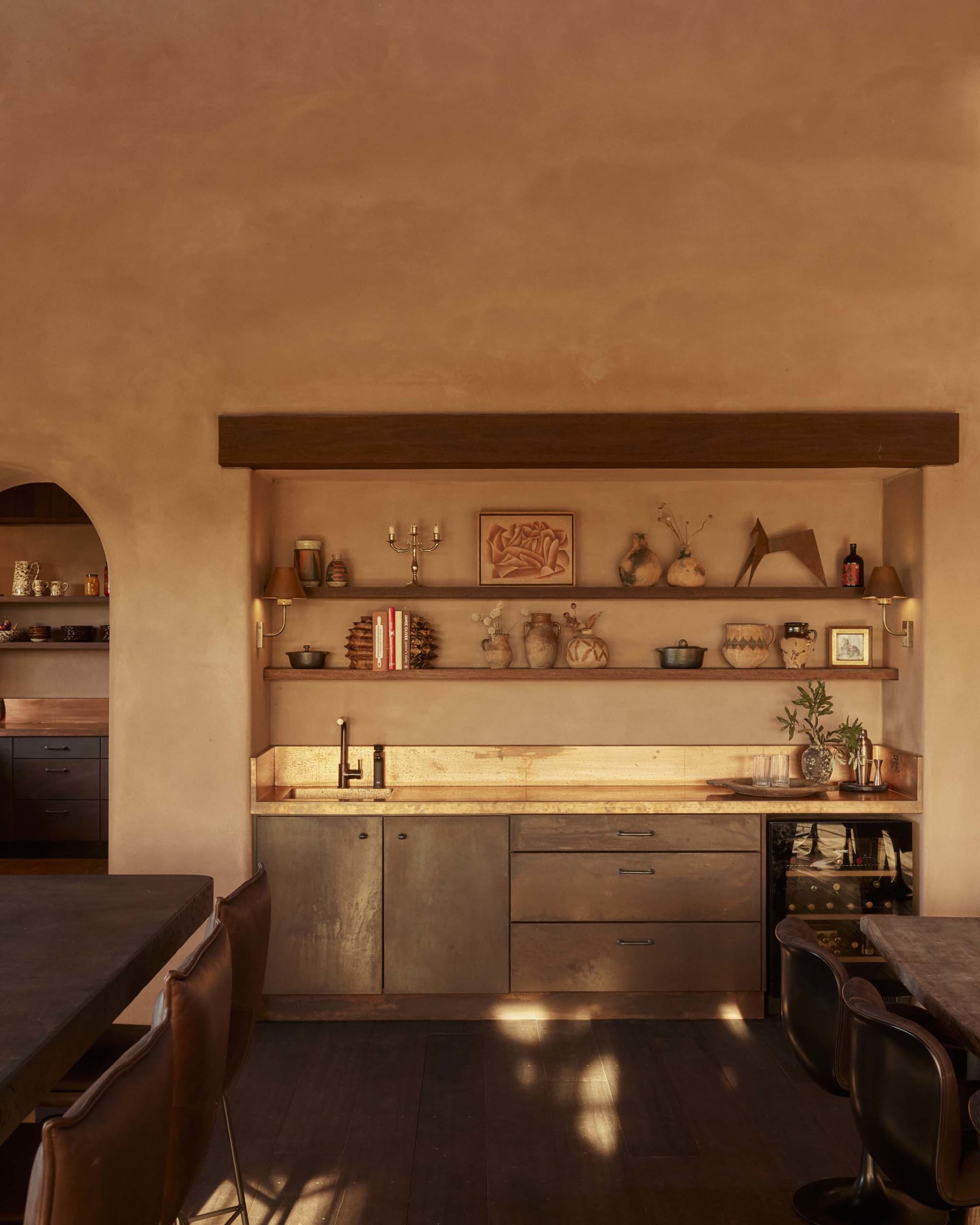 A rustic kitchen with metal shelves displaying various decorative items and a metal countertop fitted with a sink.
