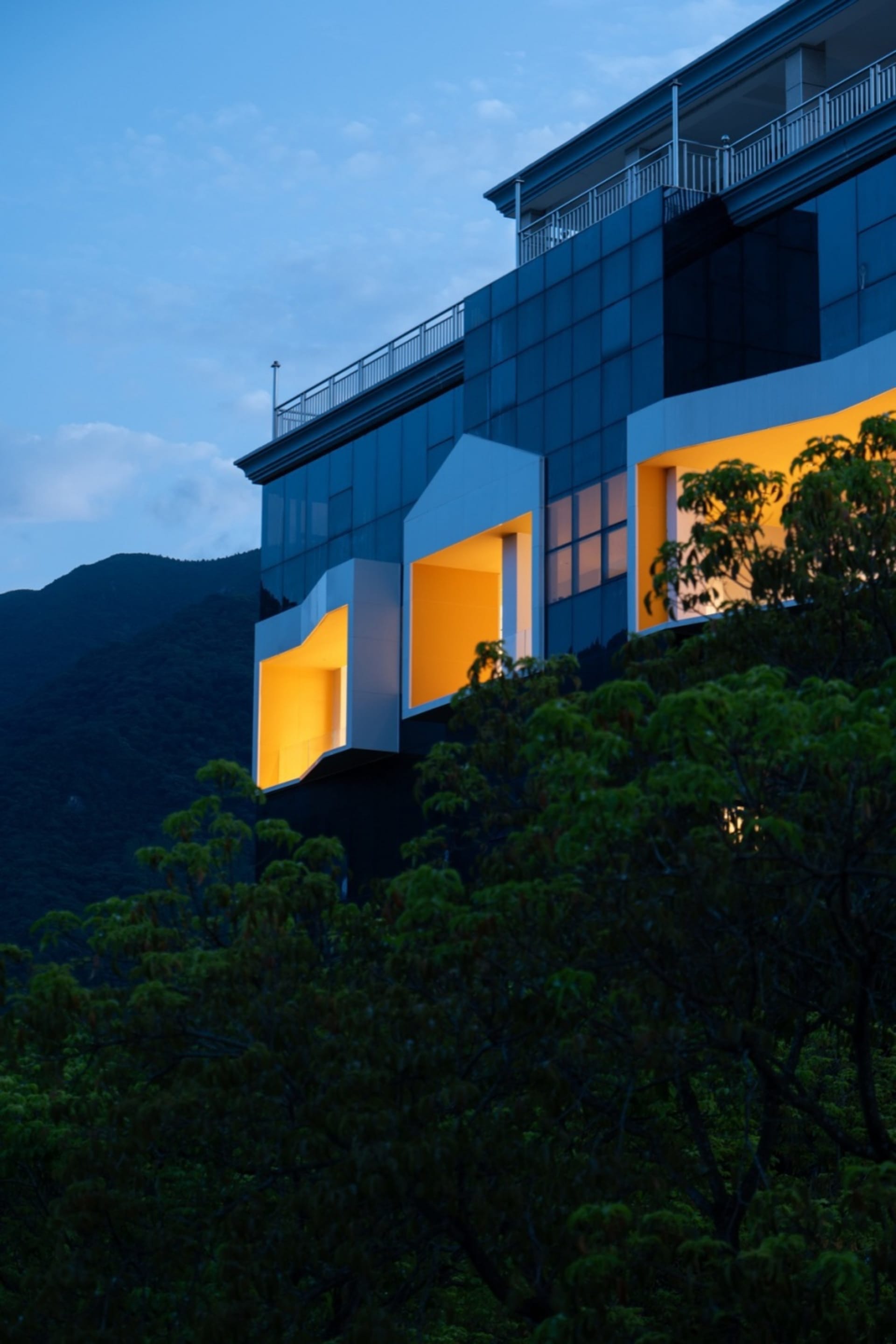 Modern building with blue cladding and glass windows at dusk.