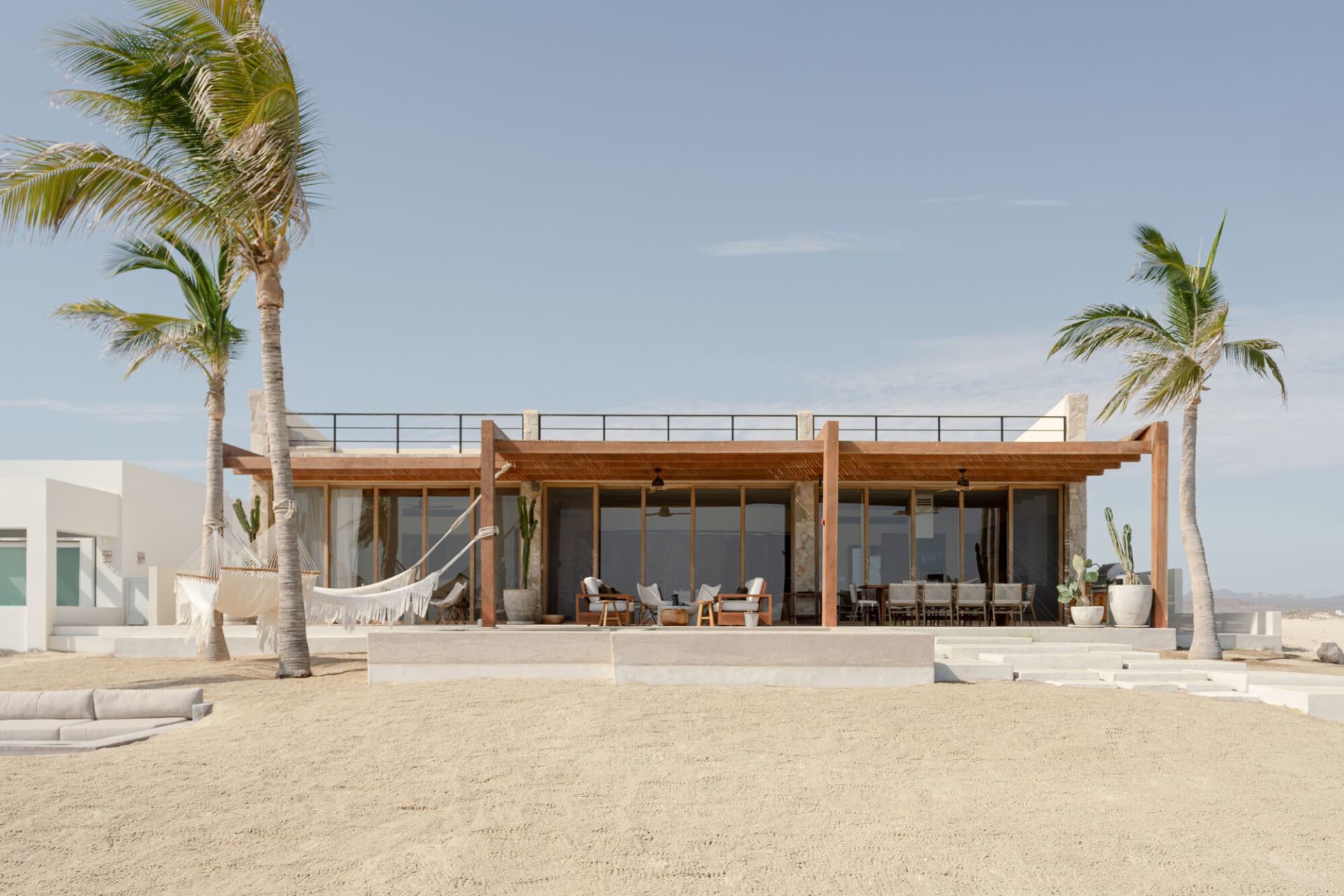 Modern residential beach house with a spacious outdoor area and sand terrace.