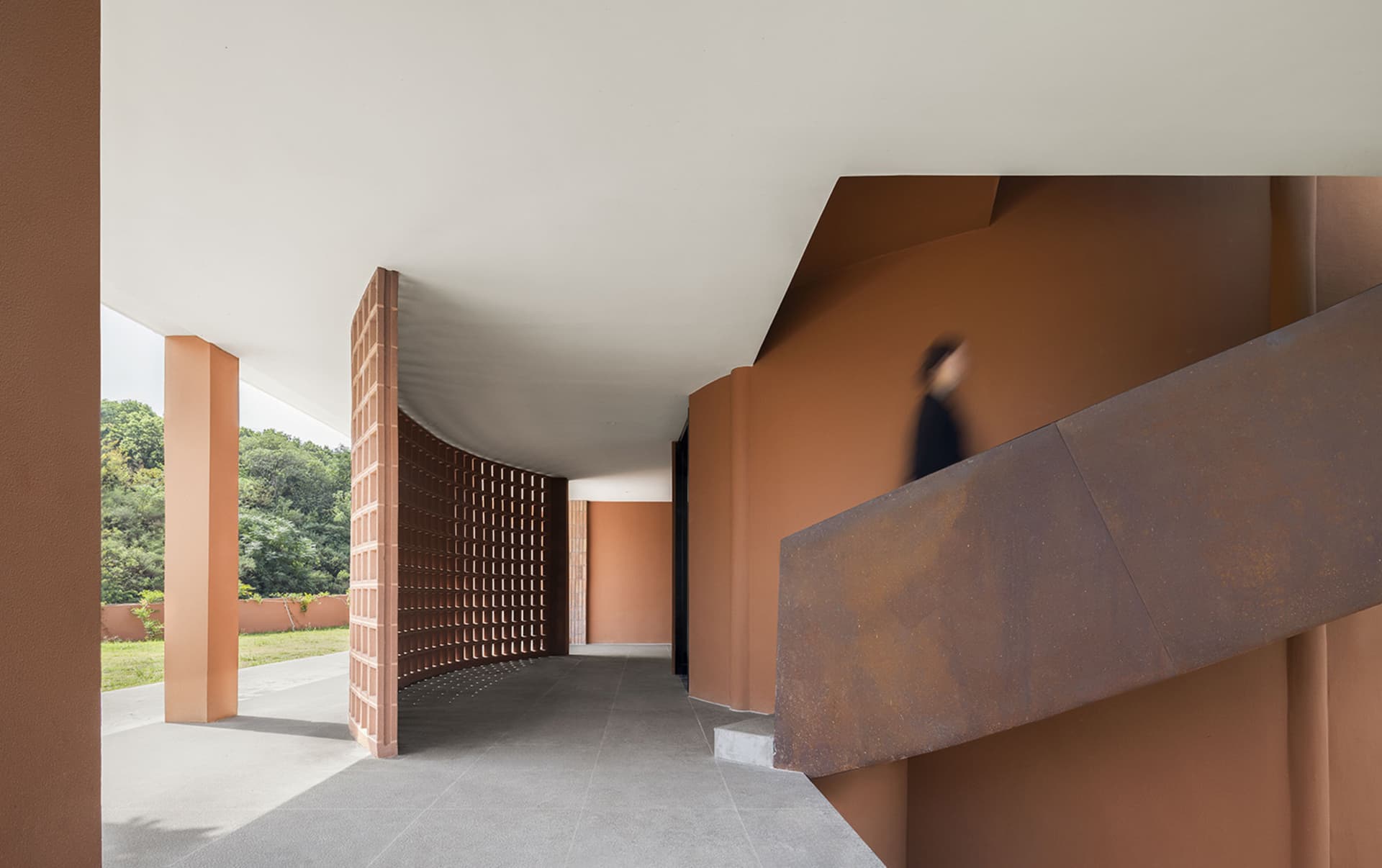 現代建築室內視圖，展示棕色穿孔金屬牆與磚柱。
