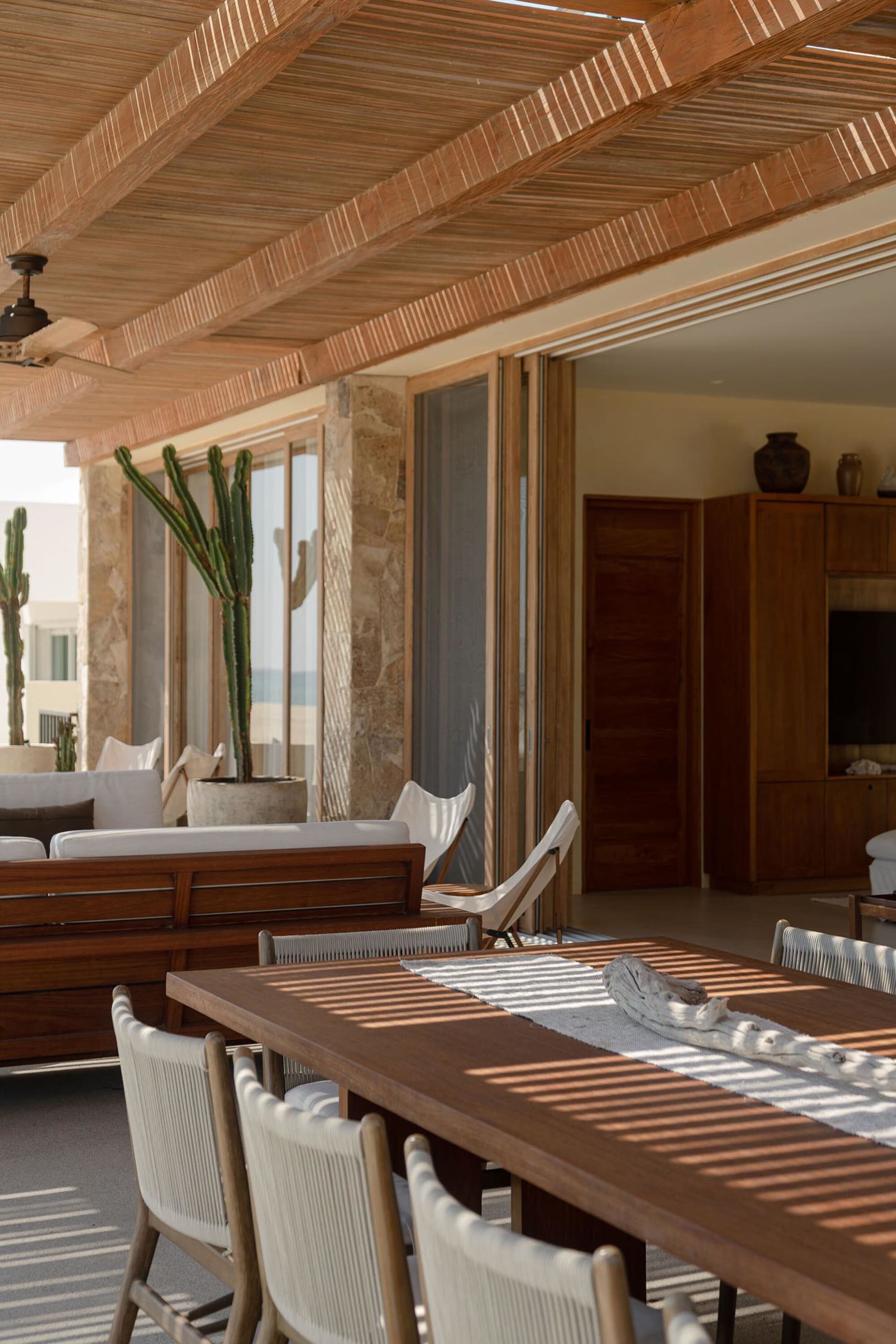 A modern interior featuring a wooden roof and seating area with cactus plants.