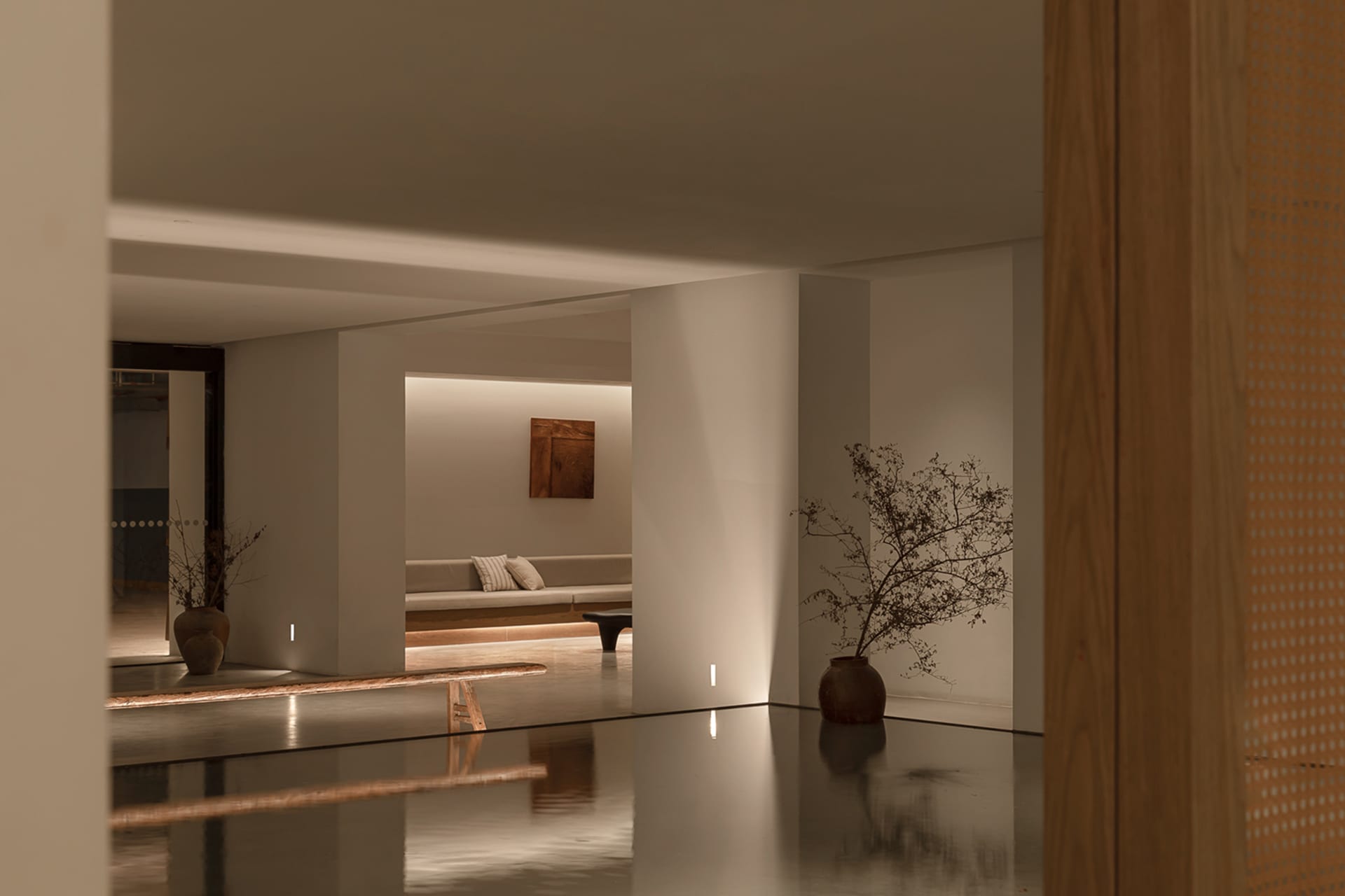 Modern minimalist living room with concrete floor, wooden furniture, and minimalist decor.