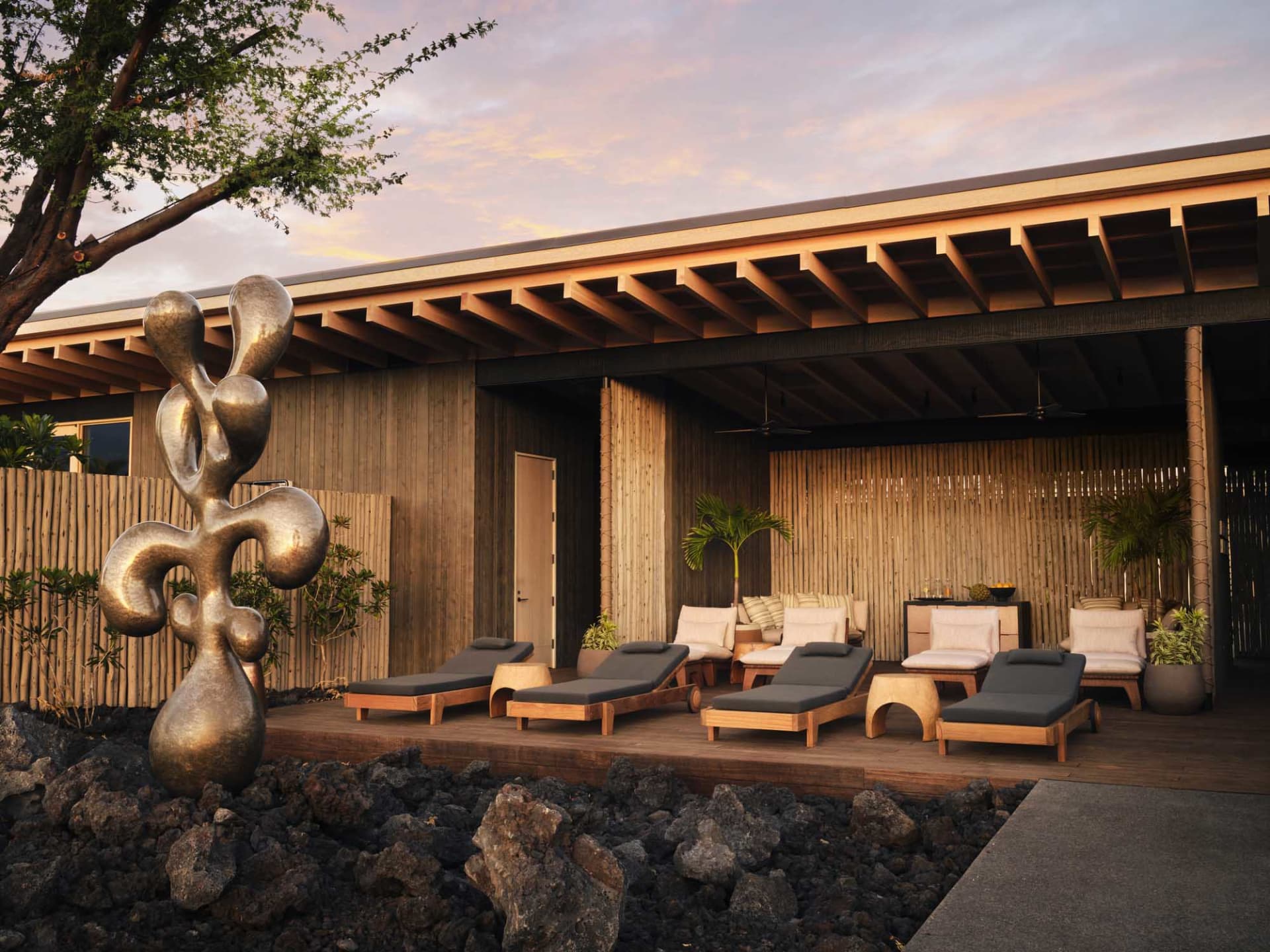 A modern residential lounge area with wooden furniture and a metal sculpture in the foreground.