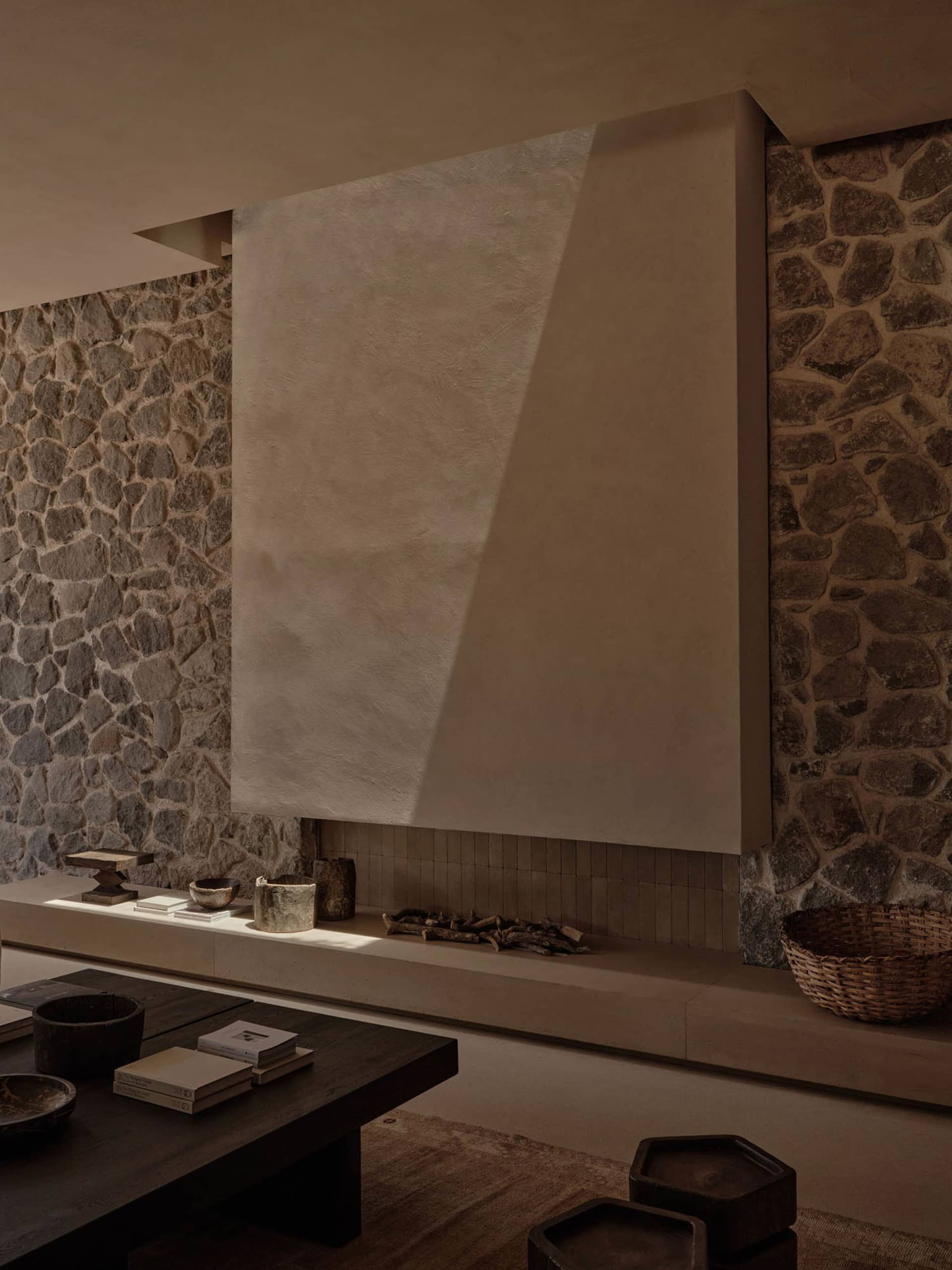 A modern interior space featuring a concrete fireplace with a stone wall backdrop.