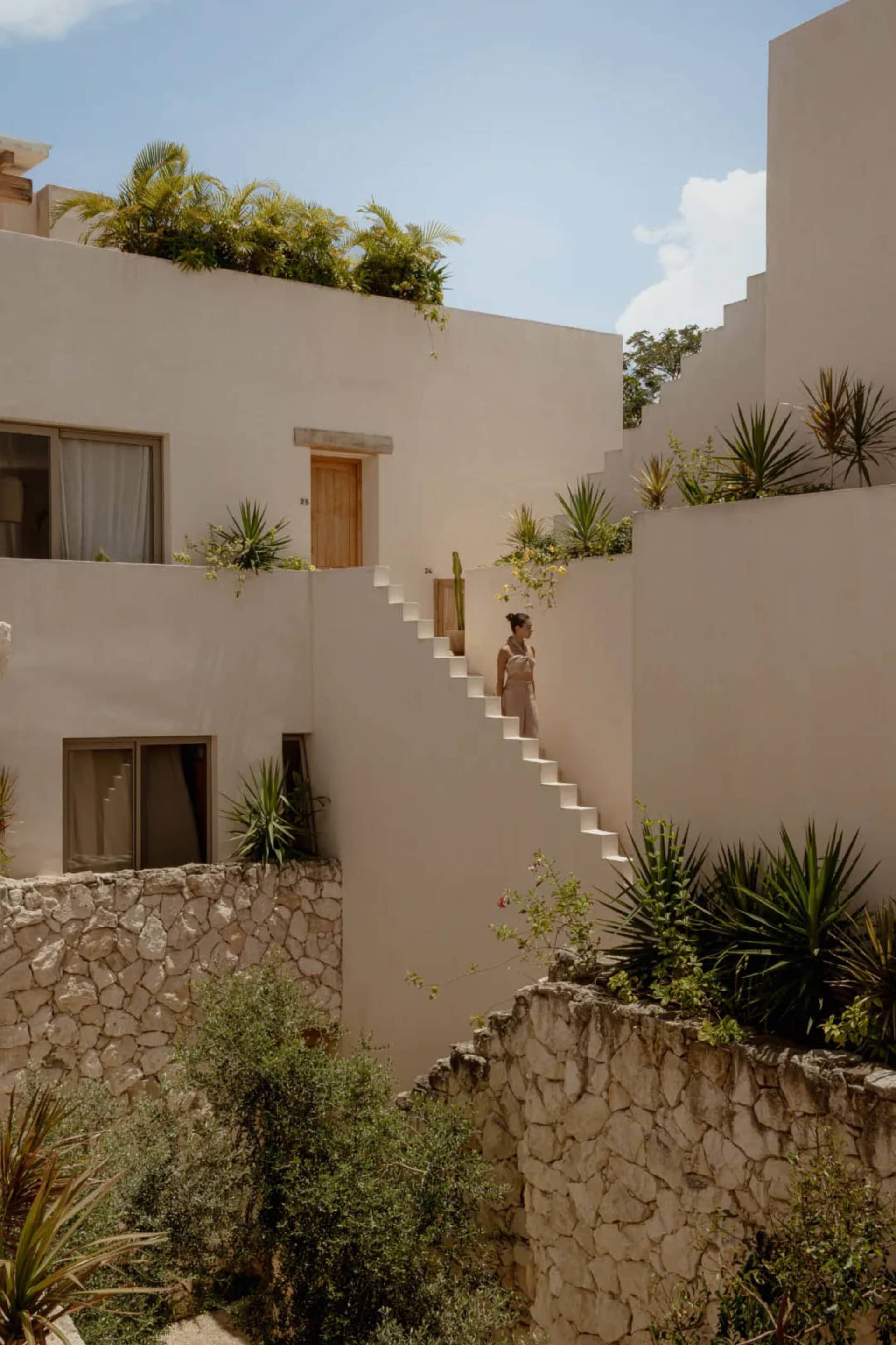 A modern residential outdoor staircase with concrete steps and stone walls surrounded by greenery.
