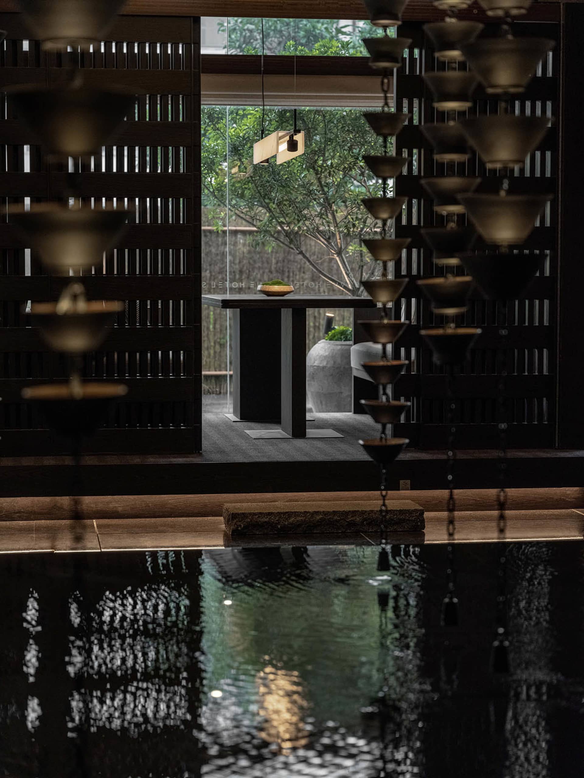 A modern spa setting with metal wall decor, featuring a minimalist design with a dark palette and a water feature.
