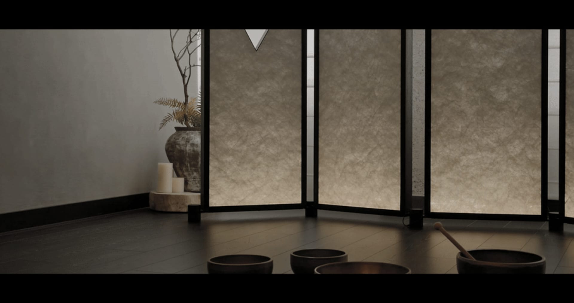 A serene spa relaxation room with stone floors, candles, and large windows allowing natural light to fill the space.