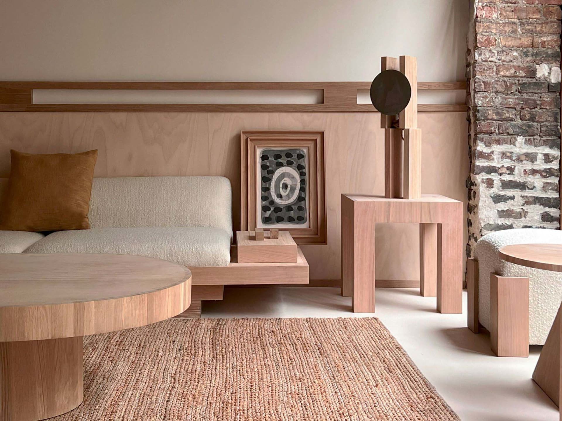 A minimalist living room featuring wooden furniture and a brick wall.