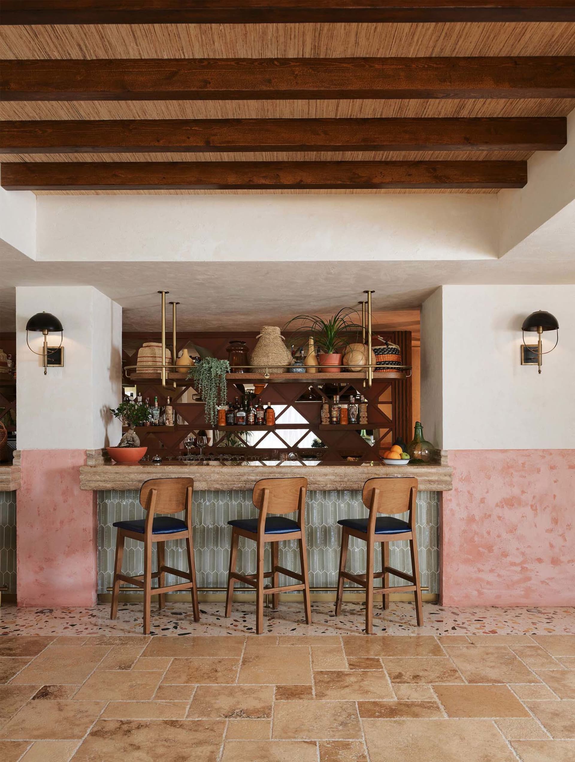 Modern bar interior with terrazzo flooring and wooden stools.