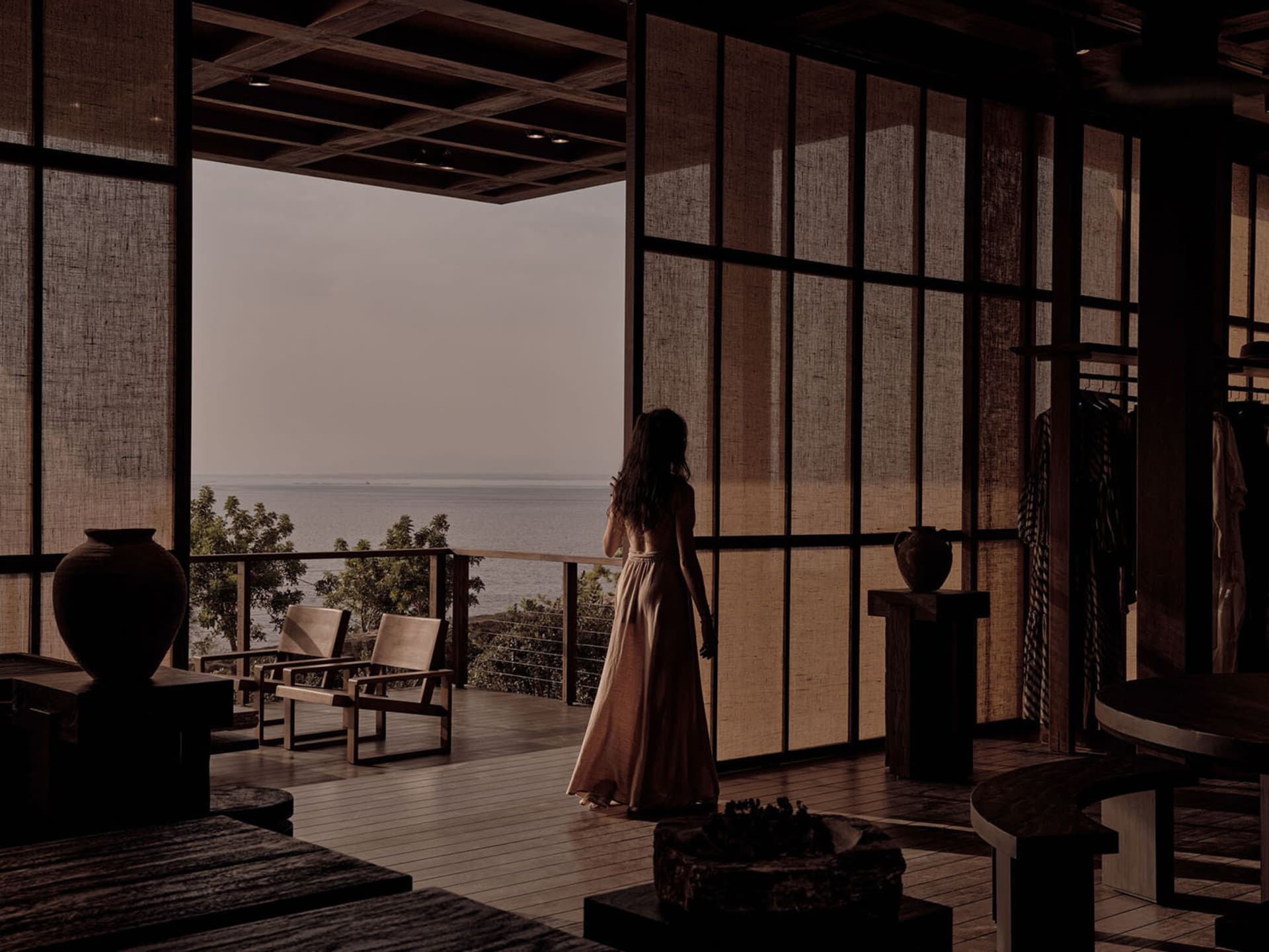 A woman standing in a modern hotel suite overlooking the ocean.