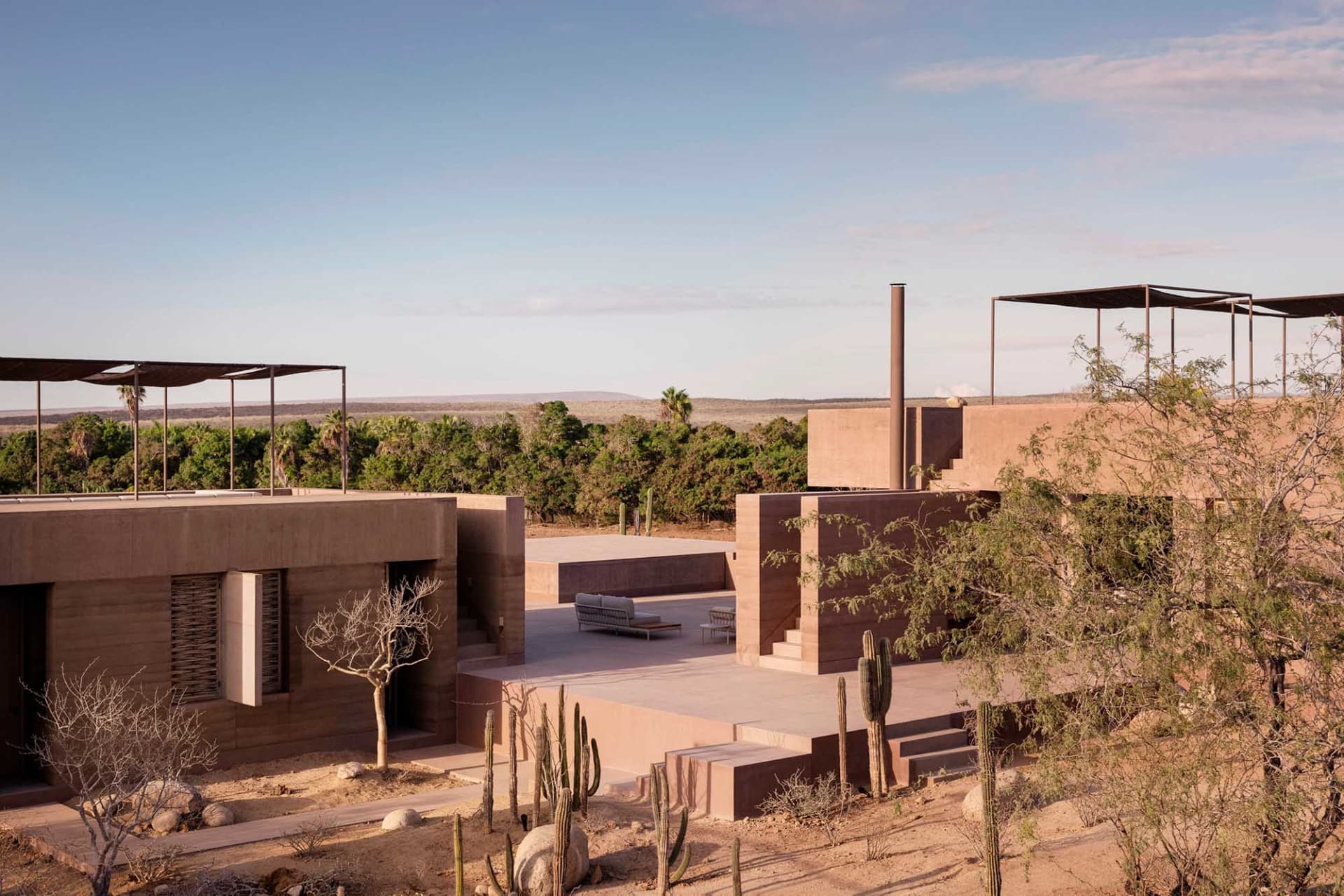 Modern vacation home with sandstone exterior in a desert landscape.