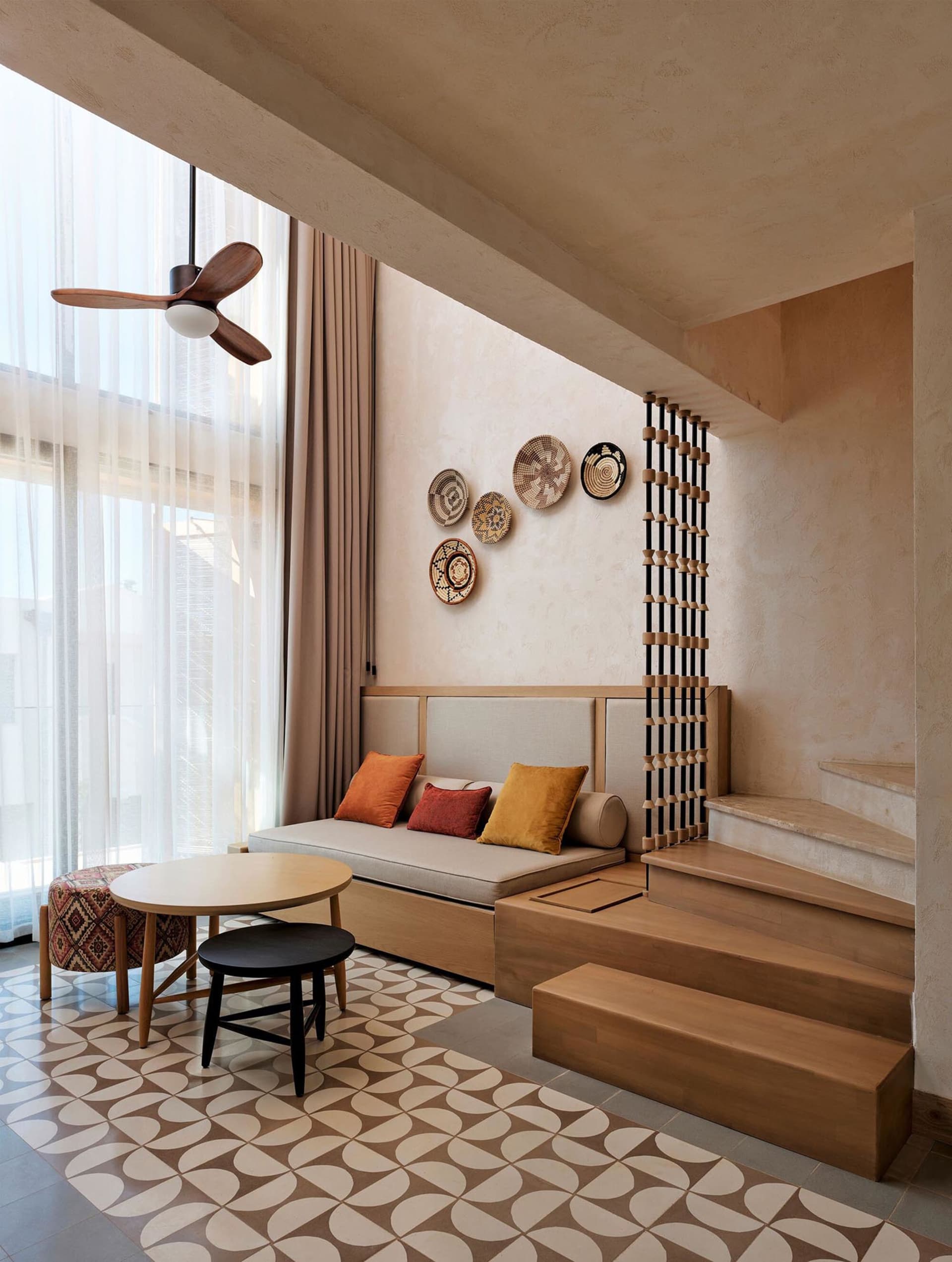 Modern interior with wooden staircase, bench, and colorful pillows.