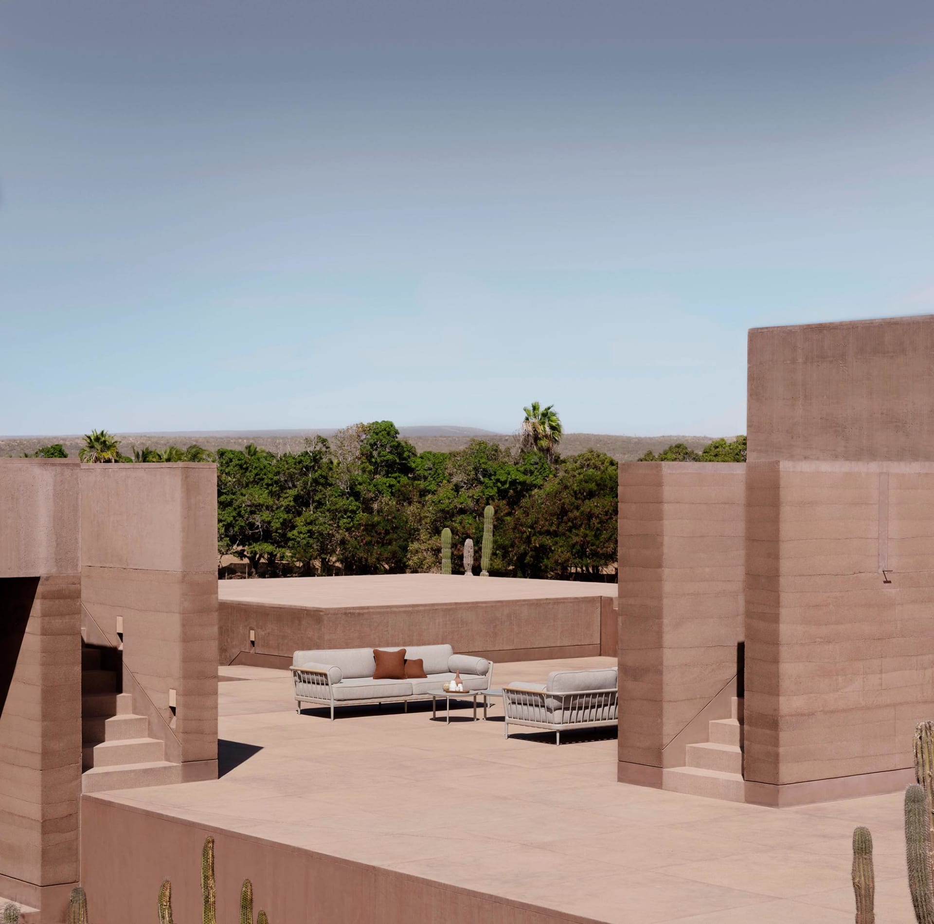 Minimalist outdoor lounge space featuring concrete walls and seating with brown accents.