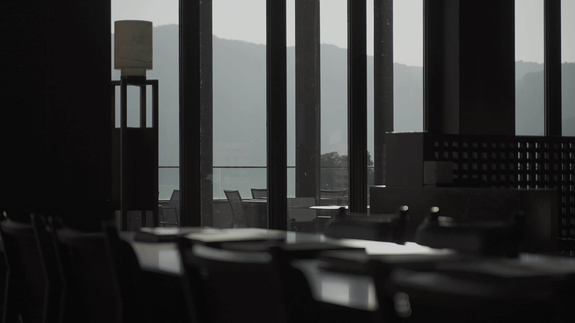 Empty modern restaurant with black glass and concrete bar, featuring sleek design and minimalist aesthetic.