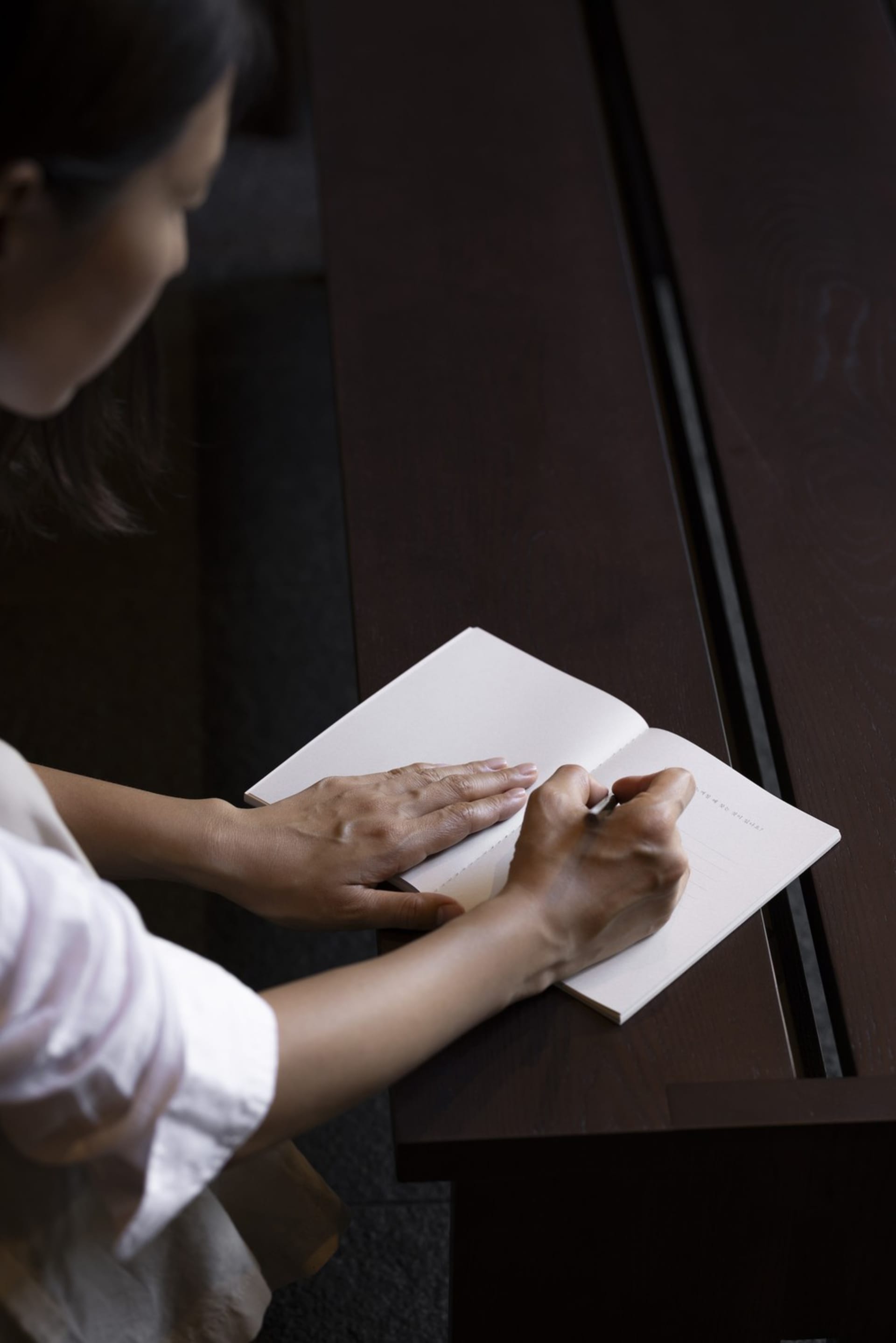 Person writing in a minimalist workspace using paper.
