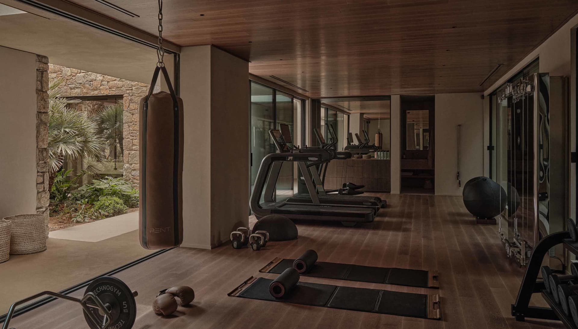 A modern indoor gym with a wooden floor and various workout equipment.